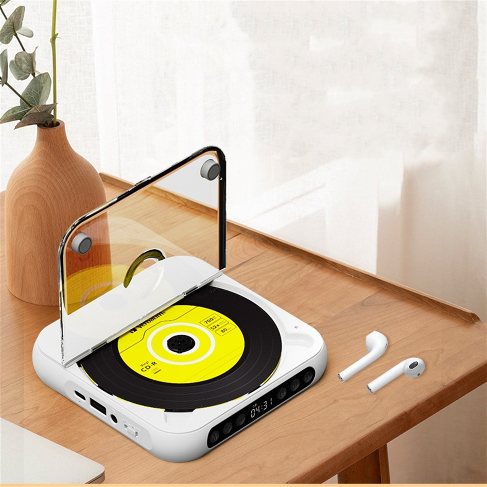 Ein weißer CD-Player mit einer gelben CD im Inneren, mit Ohrhörern auf einem Holztisch.