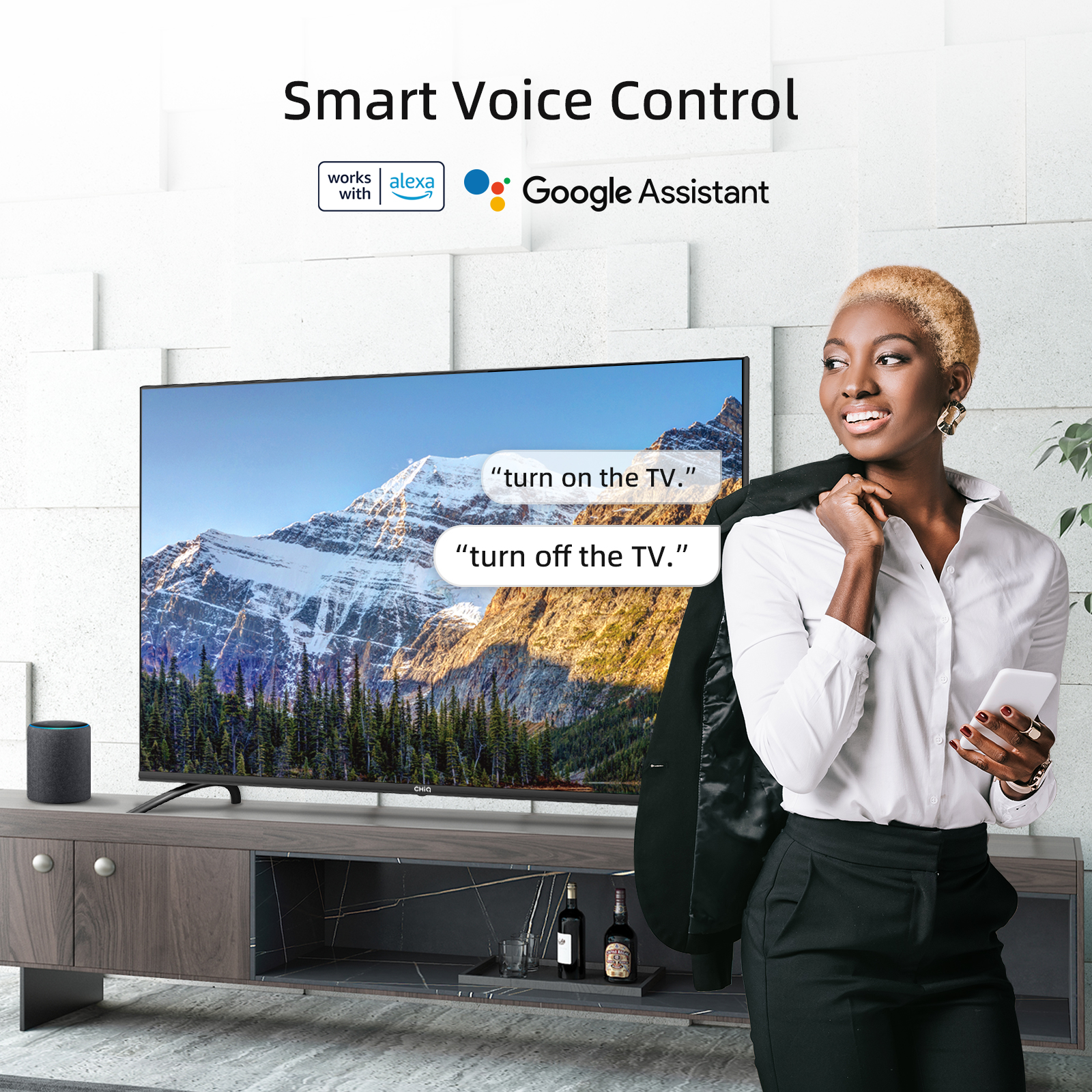 Frau mit Telefon, TV an, Sprachsteuerung, Google Assistant, Alexa, Bergpanorama, schwarzer Anzug.