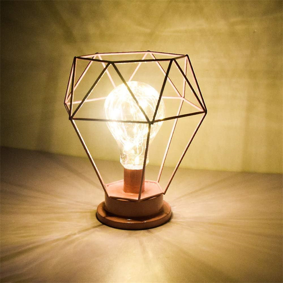 Eine beleuchtete rautenförmige Lampe mit Kupferdrahtrahmen und Glühbirne. Der Sockel ist braun.