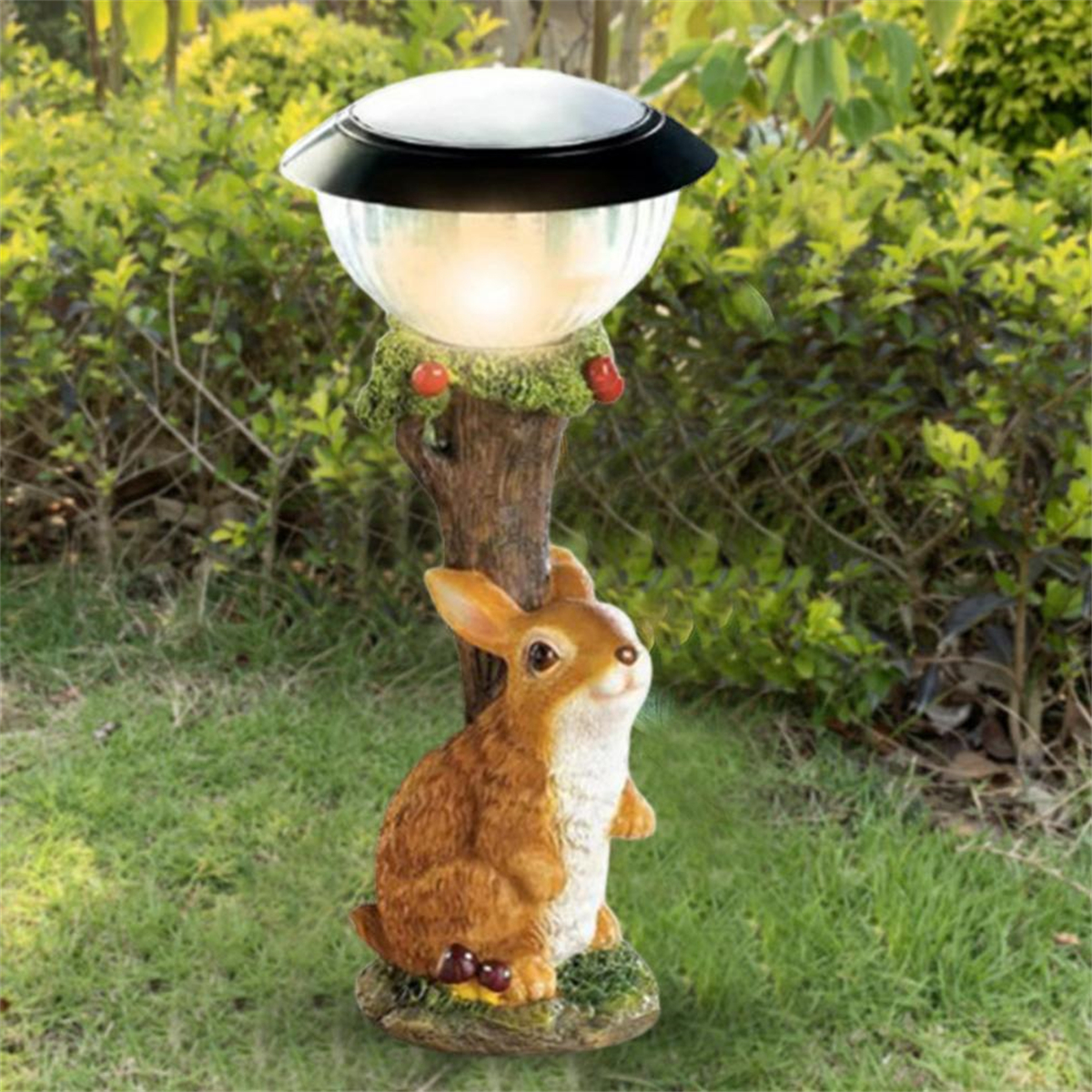 Eine Gartenleuchte mit einer Hasenstatue am Fuß, umgeben von Grün.