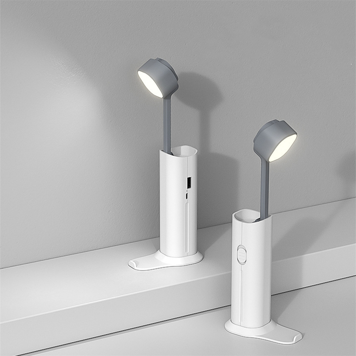 Zwei weiße und graue Schreibtischlampen mit schlankem Design.