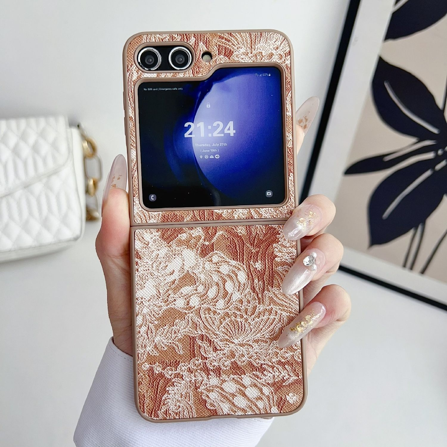 Eine Hand hält eine gold gemusterte Handyhülle mit einem Handy, das die Zeit anzeigt.
