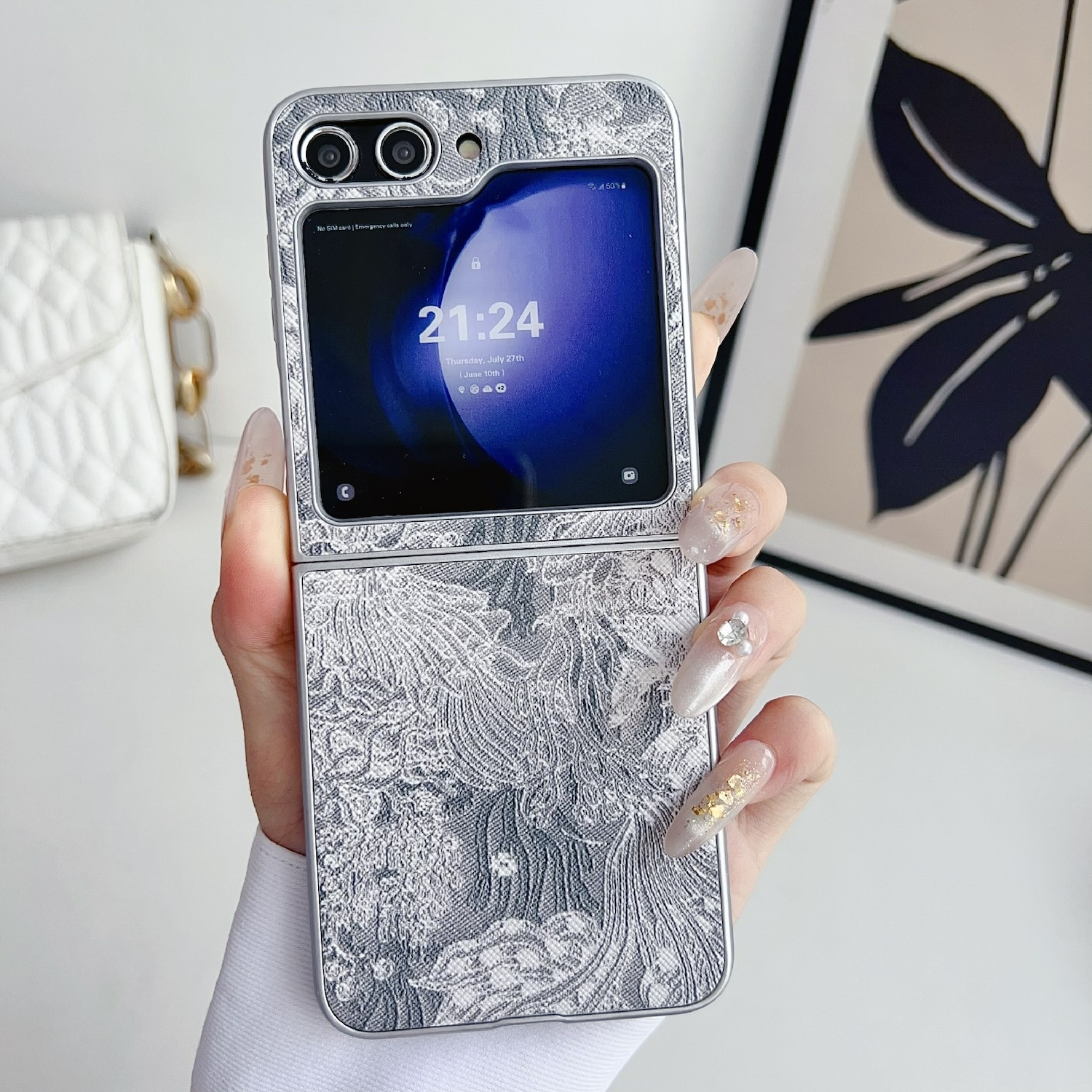 Nahaufnahme einer zusammengeklappten Handyhülle mit silbernem Design. Eine Hand hält das Telefon.