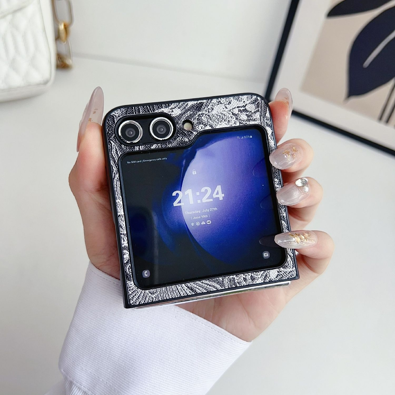 Die Hand einer Person, die ein zusammenklappbares Telefon in einer Hülle hält. Das Telefon ist geöffnet und zeigt eine Uhr.