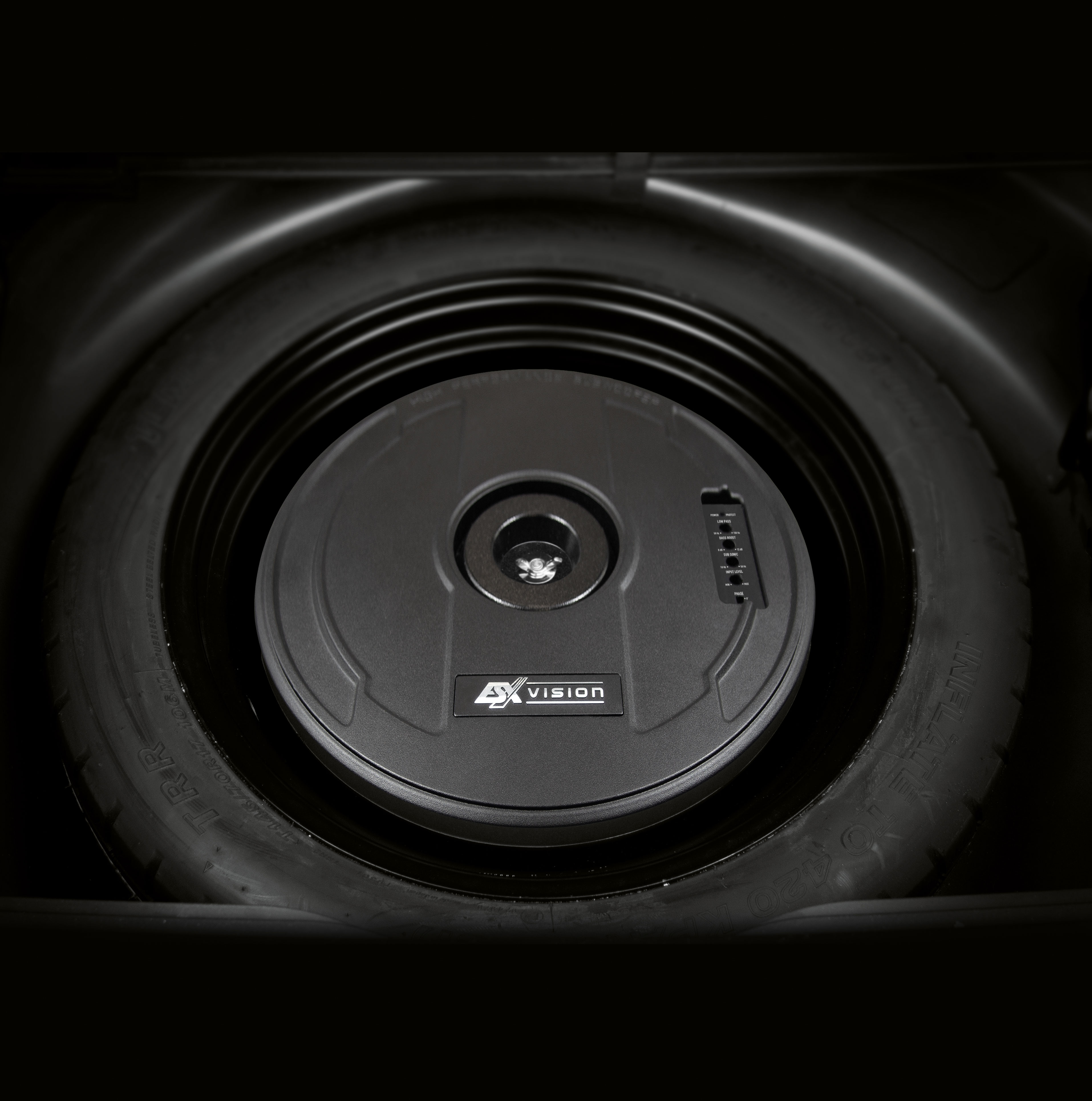Schwarzer Subwoofer im Ersatzreifenraum eines Autos.