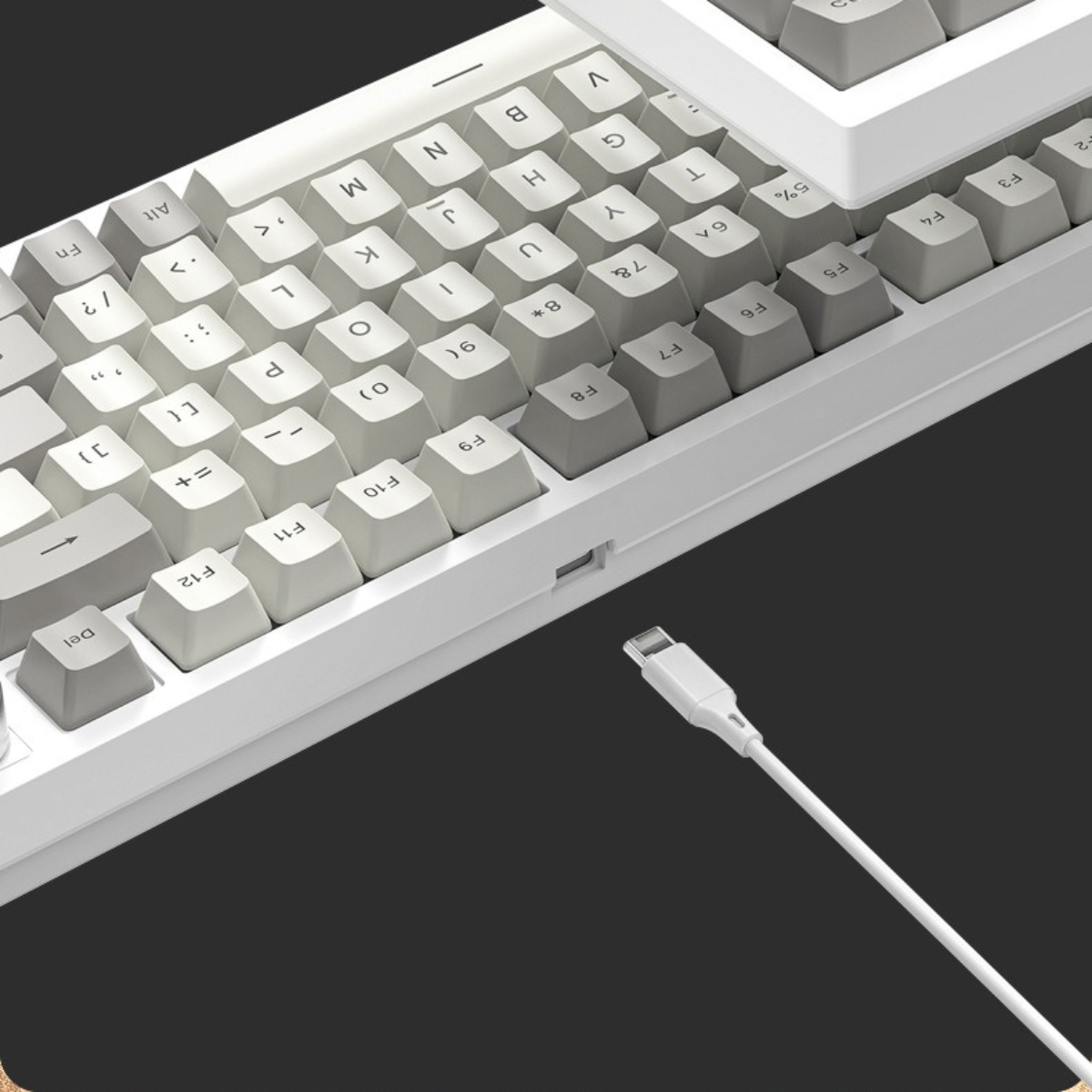 Weiße und graue Tastatur mit angeschlossenem USB-Kabel. Dunkelgrauer Hintergrund.