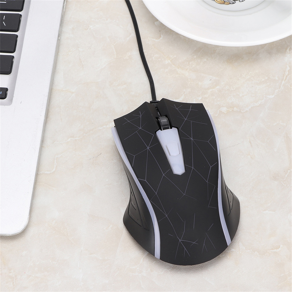 Schwarze Computermaus mit weißen Akzenten und einem Scrollrad. Sie ist mit einem Laptop verbunden.