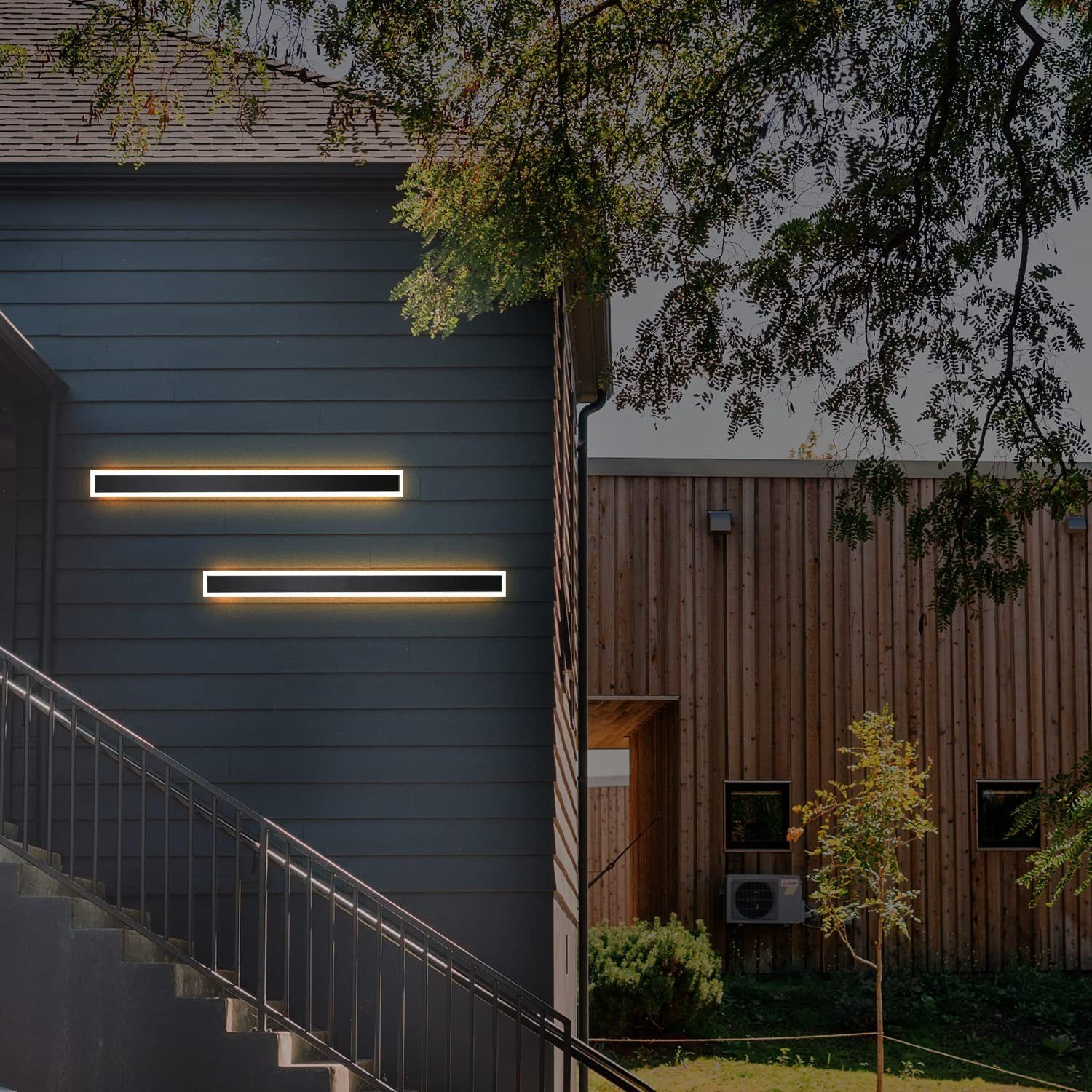 Due luci rettangolari luminose su un muro blu scuro, accanto a un edificio in legno con vegetazione.
