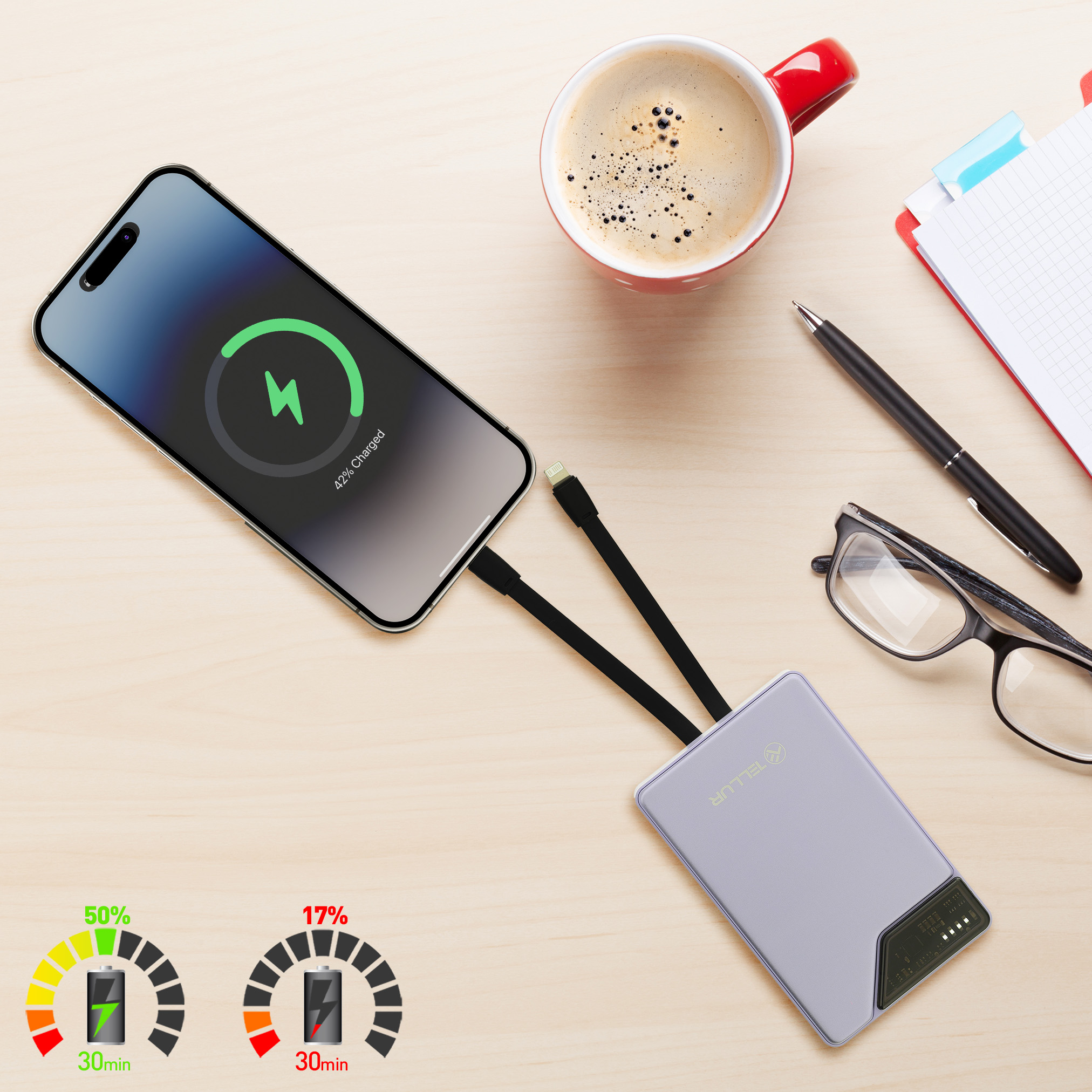 Telefon ładujący się z power banku z kubkiem, długopisem i okularami na stole.