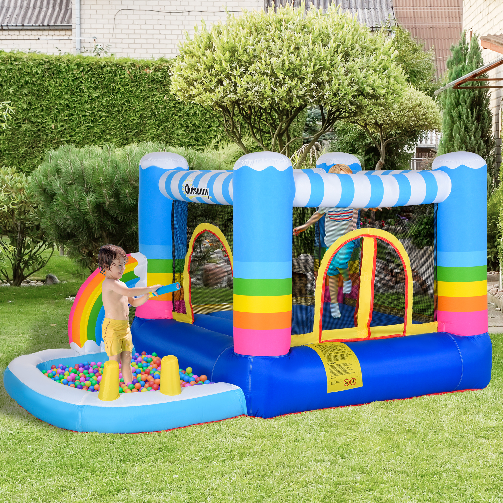 Bambini in un castello gonfiabile con un getto d'acqua. Sono presenti anche palline e un arcobaleno. Erba verde.