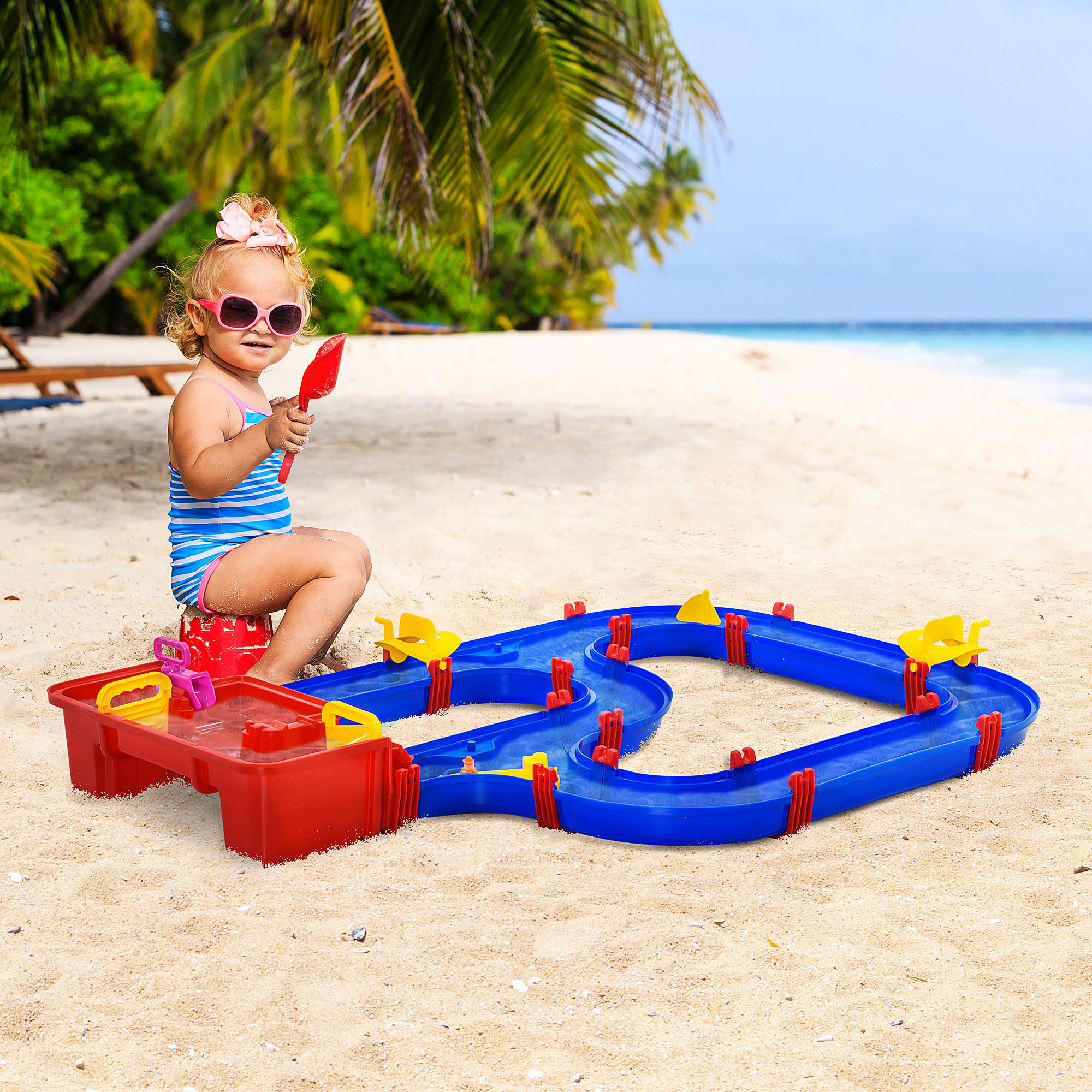 Un bambino sulla spiaggia gioca con un giocattolo acquatico. Mare e palme sullo sfondo.