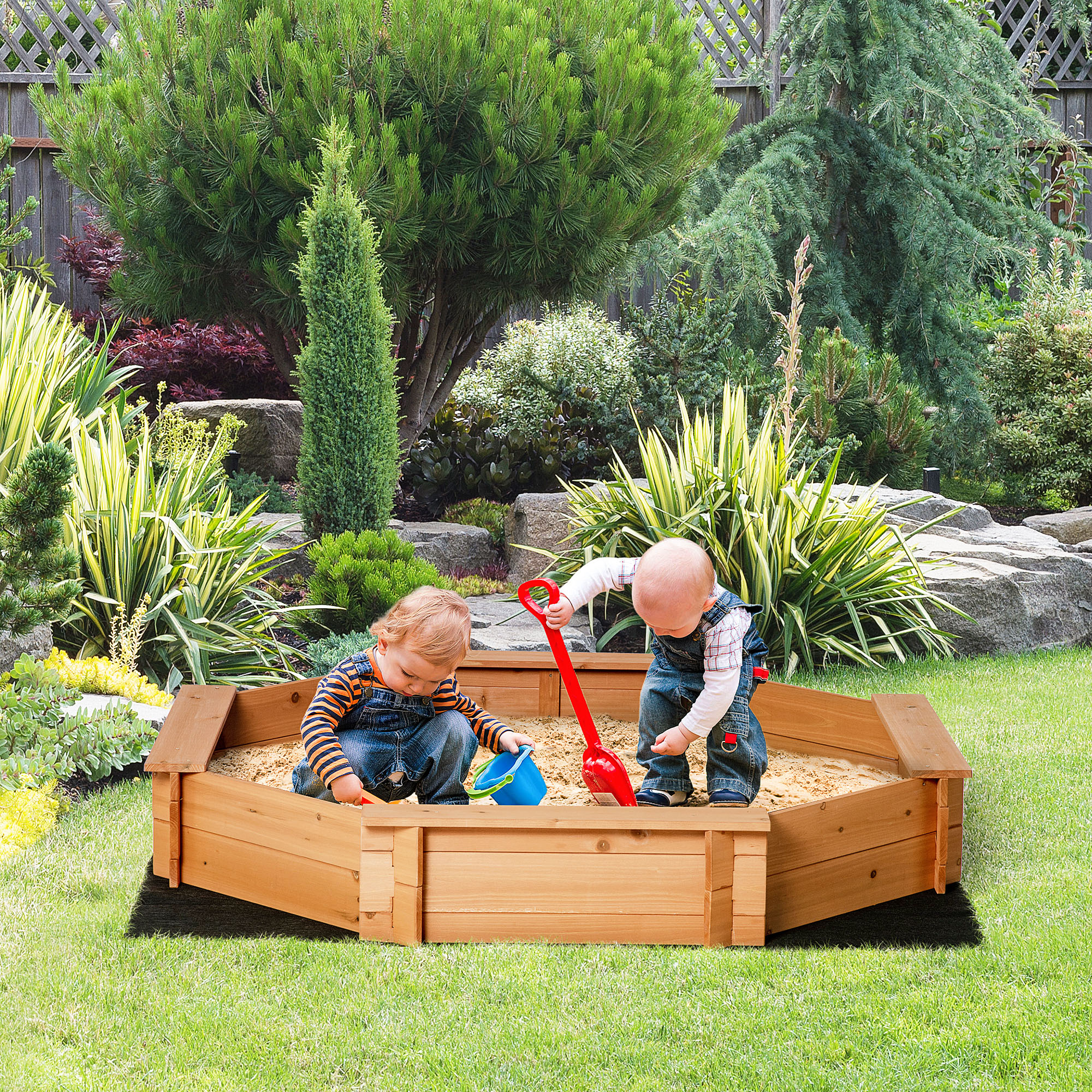 Due bambini che giocano in una sabbiera di legno in un giardino.