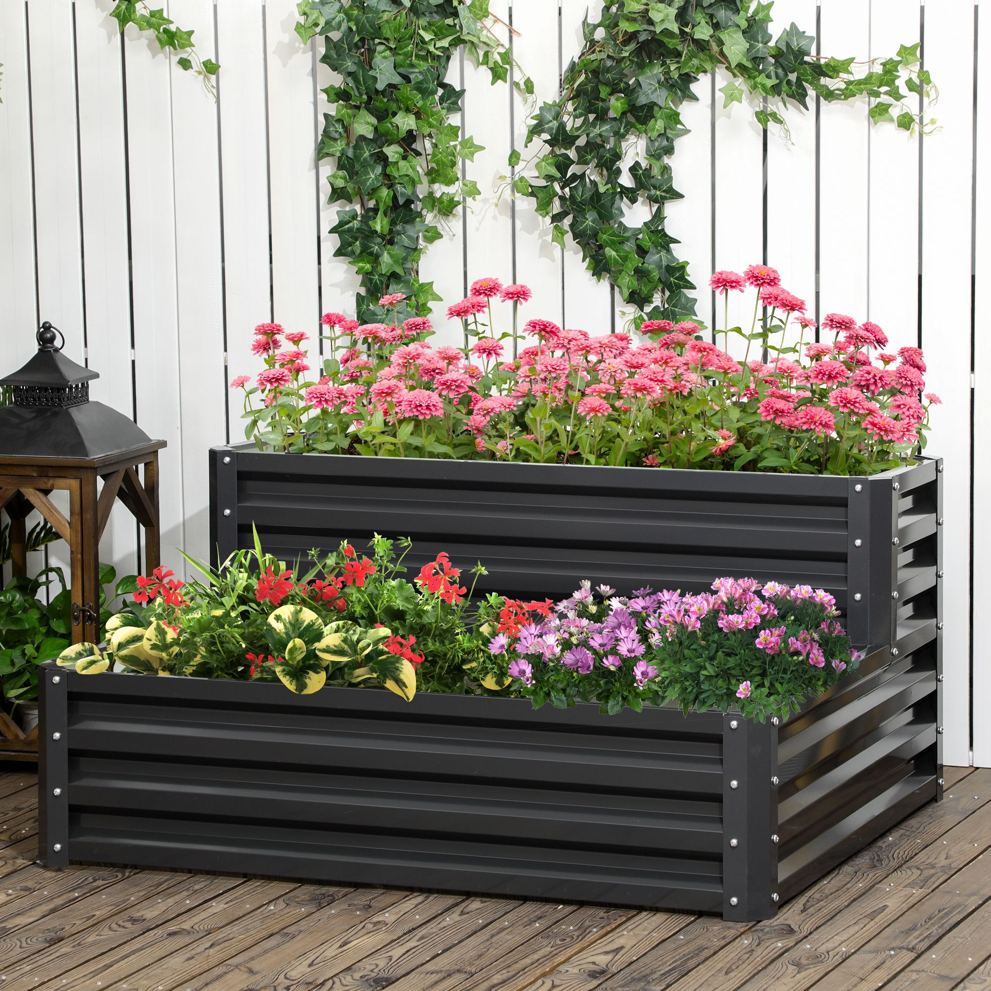 Due aiuole rialzate in metallo nero sono piene di fiori colorati. Si trovano su un ponte di legno.