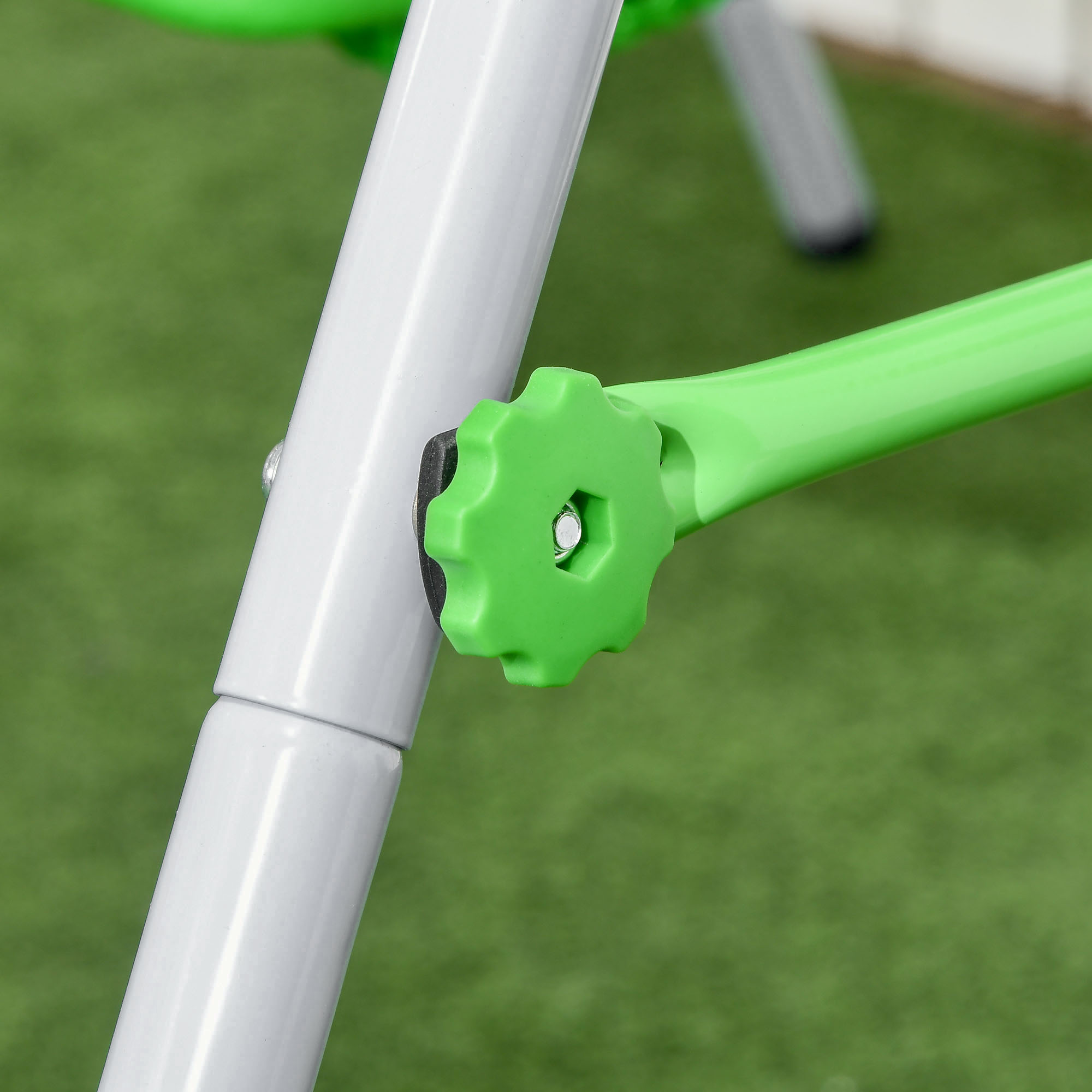 Primo piano di una manopola verde a forma di ingranaggio attaccata a un palo bianco su una superficie erbosa verde.