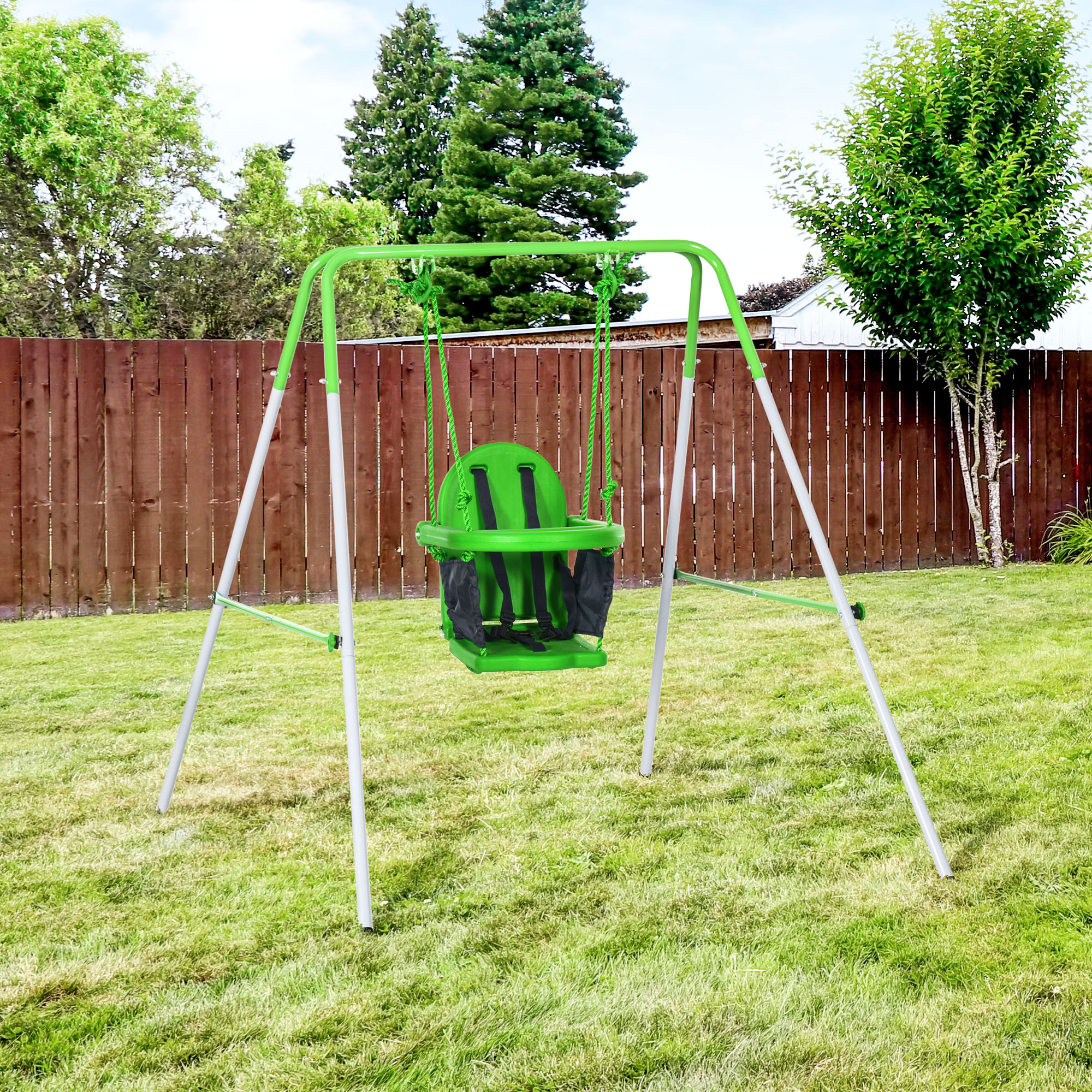 Un'altalena verde con un seggiolino verde in un cortile erboso.