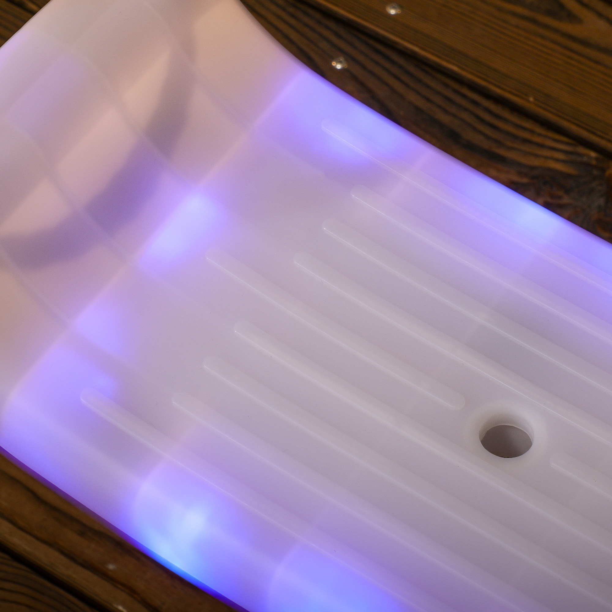 Primo piano di una superficie di plastica bianca illuminata con luci viola e blu visibili dal basso.