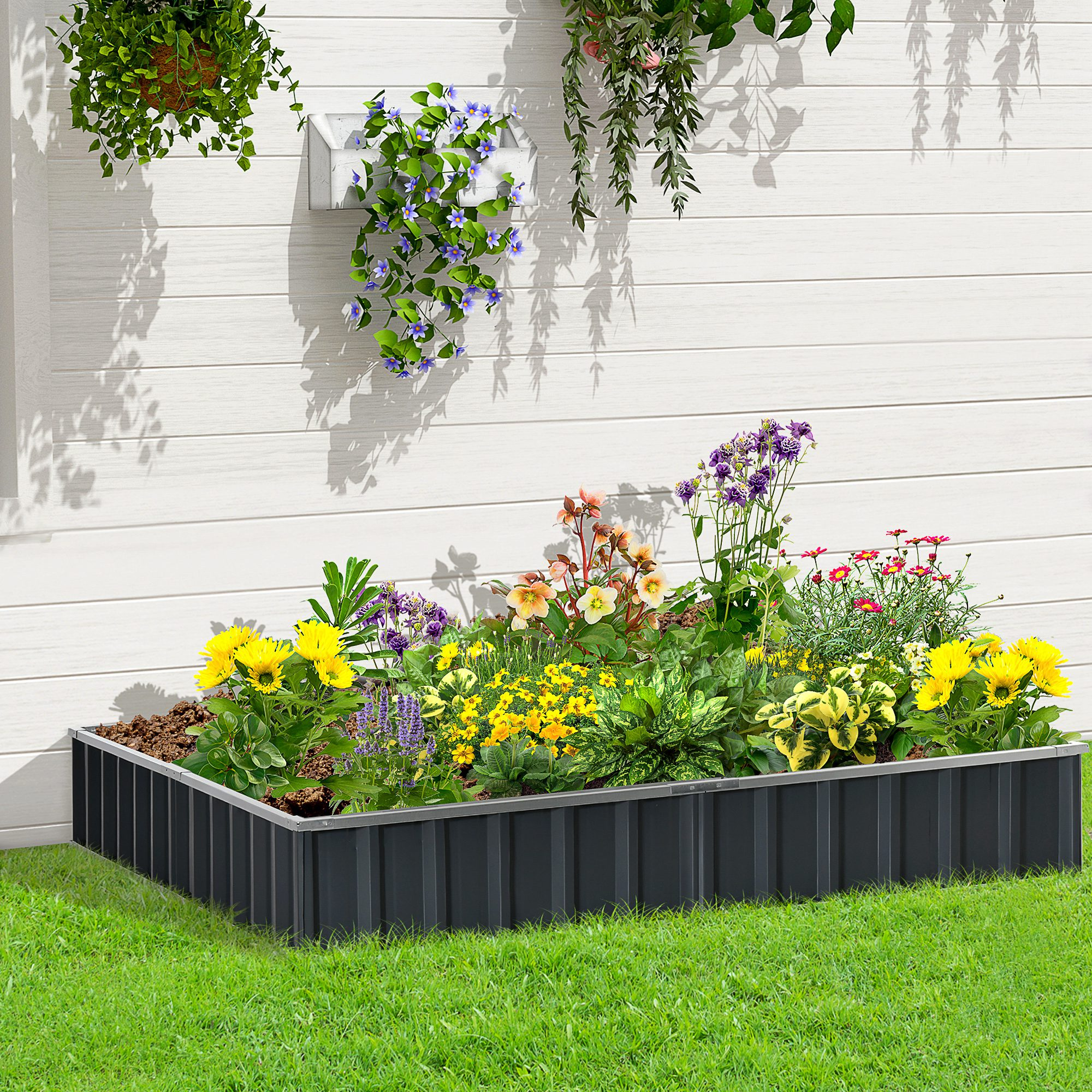Una fioriera rettangolare nera piena di vari fiori colorati su erba verde.