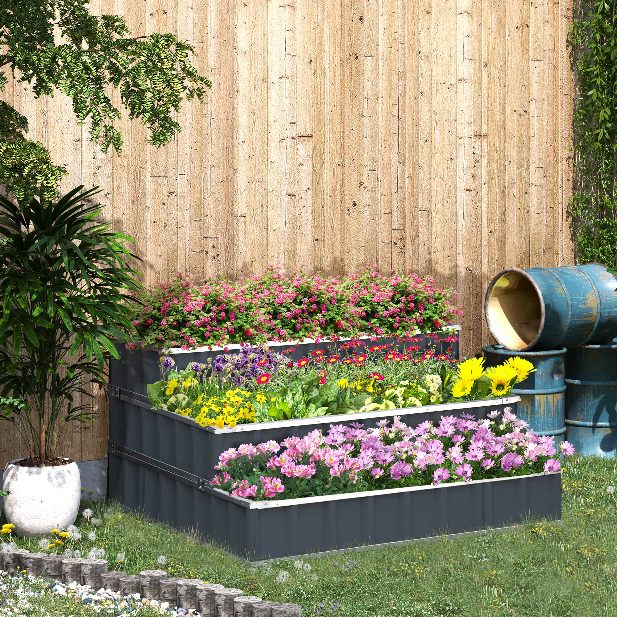 Ein gestuftes Gartenbeet mit blühenden Blumen und Fässern im Hintergrund.