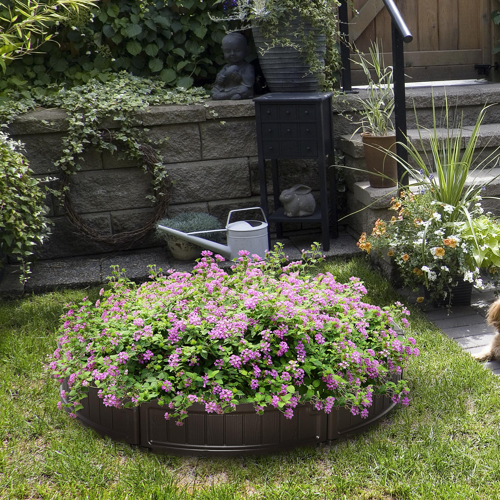 Aiuola rotonda con fiori rosa e verde, in un ambiente giardino.