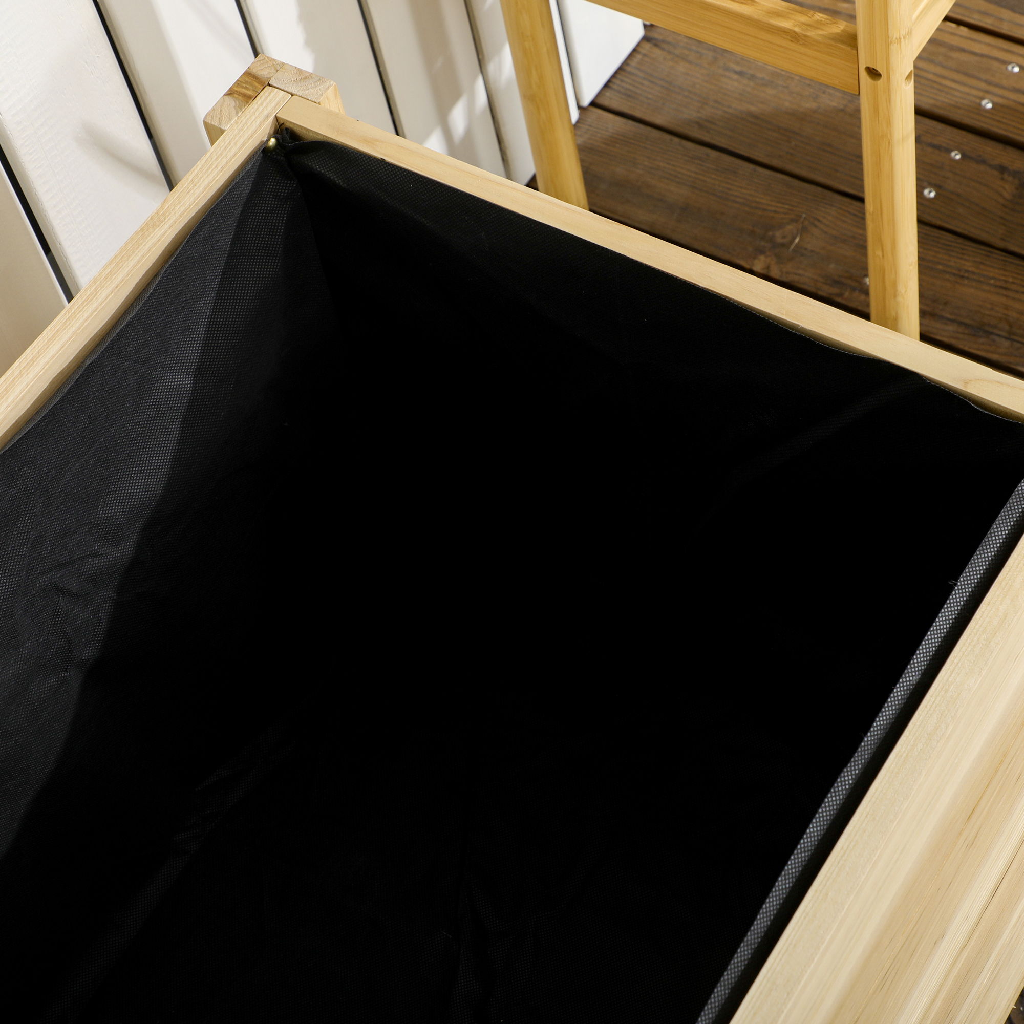 Primo piano del rivestimento in tessuto nero di una fioriera in legno. Marrone chiaro.