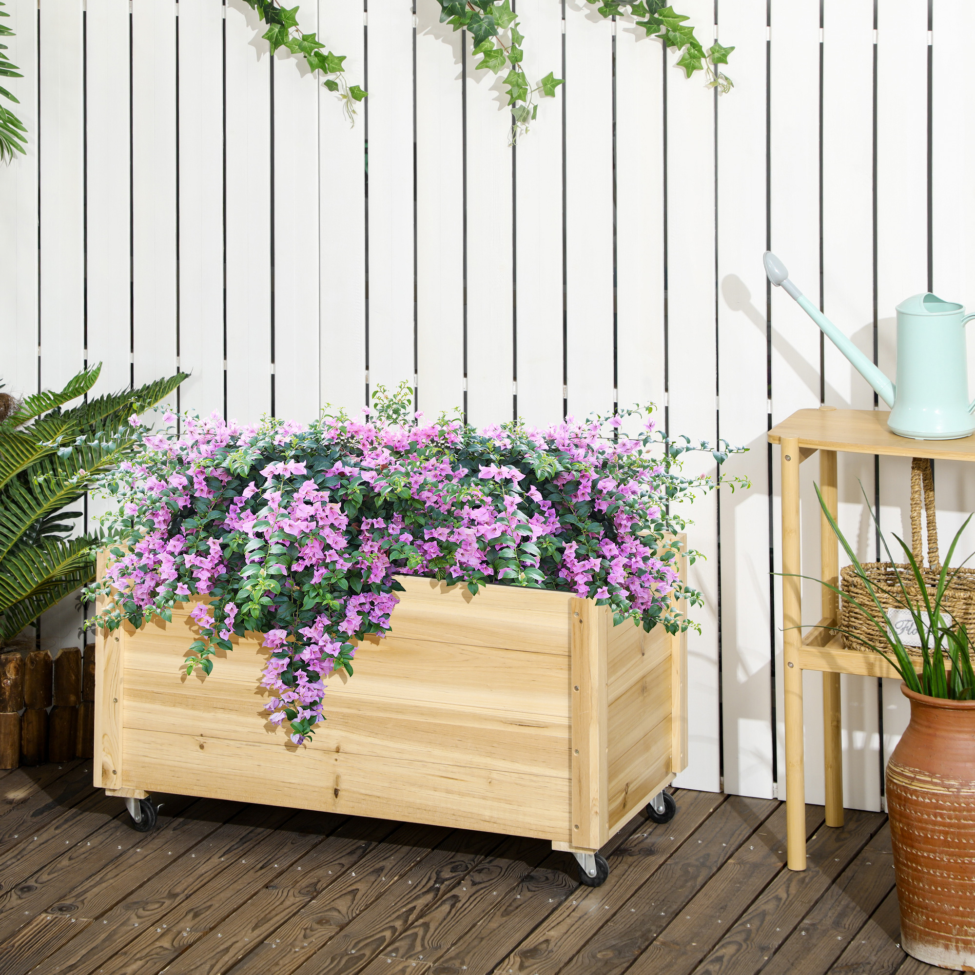 Fioriera in legno su ruote, con fiori viola, sfondo bianco.