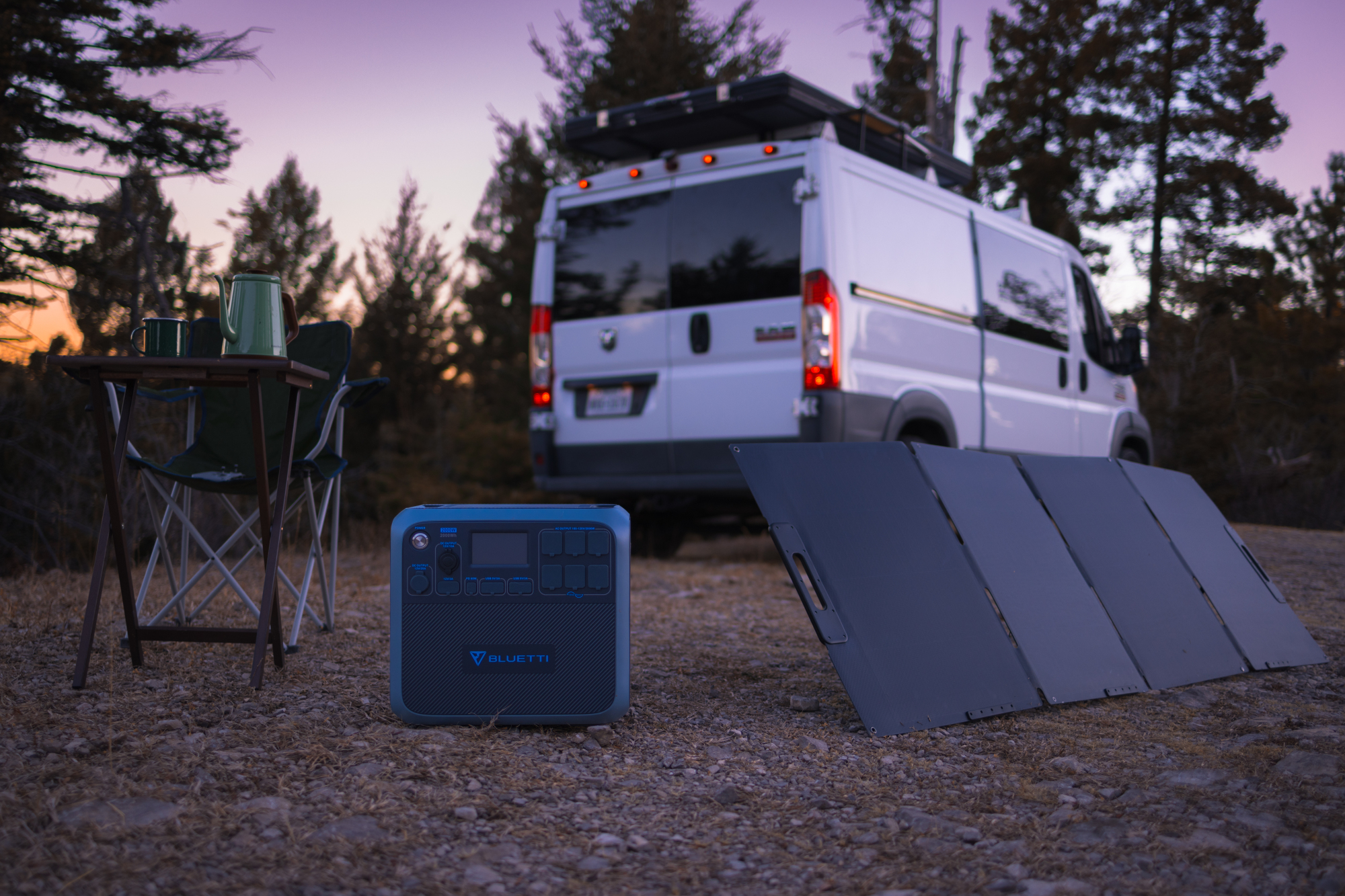 Ein Van parkt in einem Wald. Eine tragbare Stromstation und ein Solarpanel sind im Vordergrund.