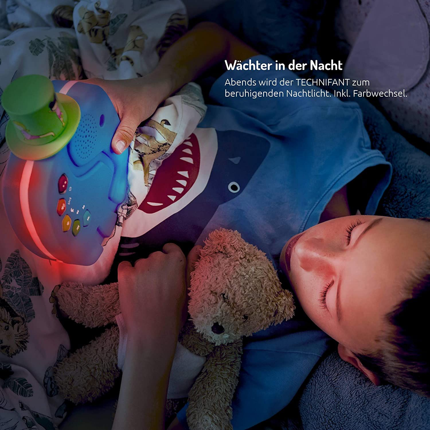 Ein Kind schläft mit einem Teddybären, in der Nähe eines blauen Elefanten-Nachtlichts. Text auf Deutsch: 'Wächter in der Nacht'.