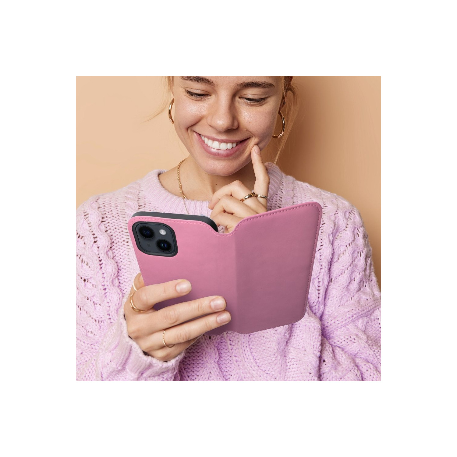 Una donna sorridente che tiene e guarda una custodia rosa con un telefono all'interno.