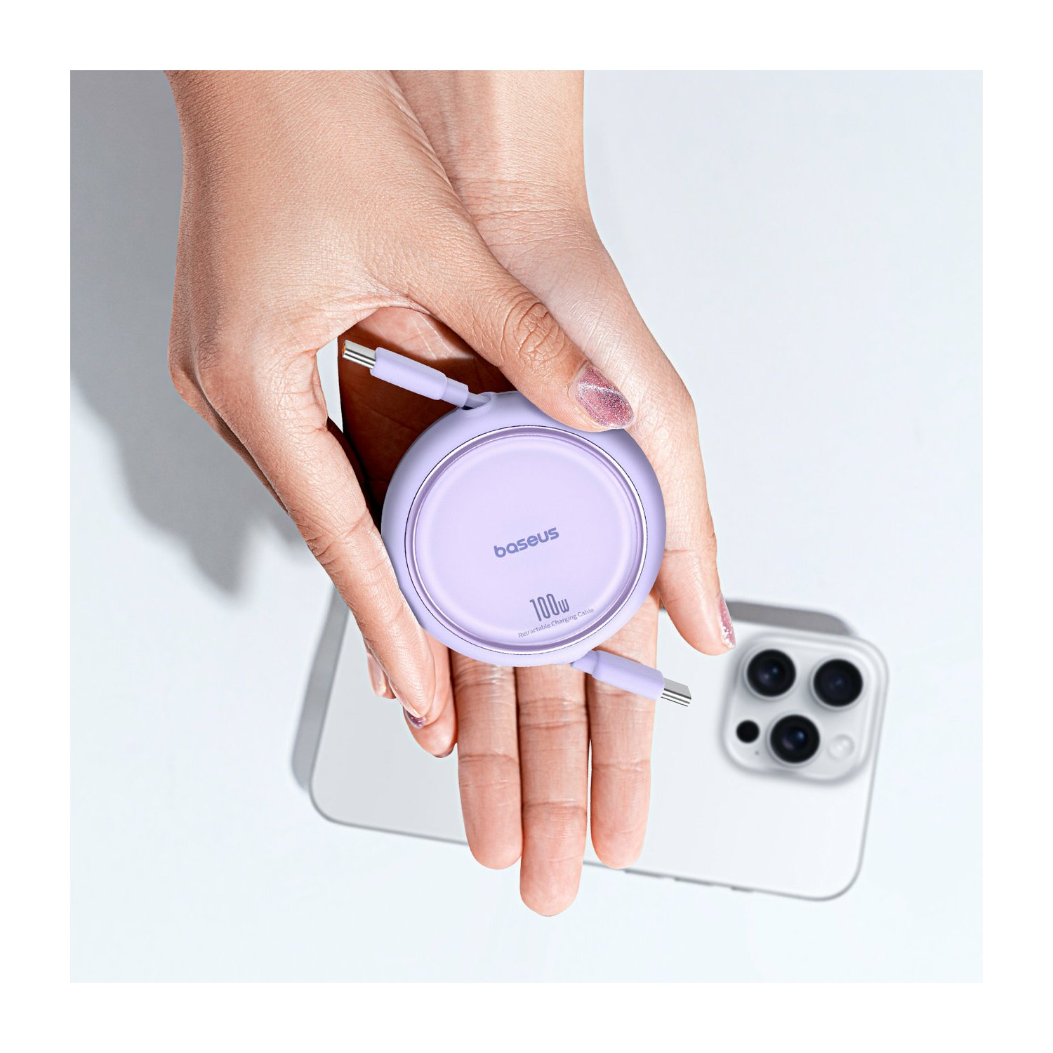 Dłonie osoby trzymającej fioletową ładowarkę bezprzewodową Baseus.