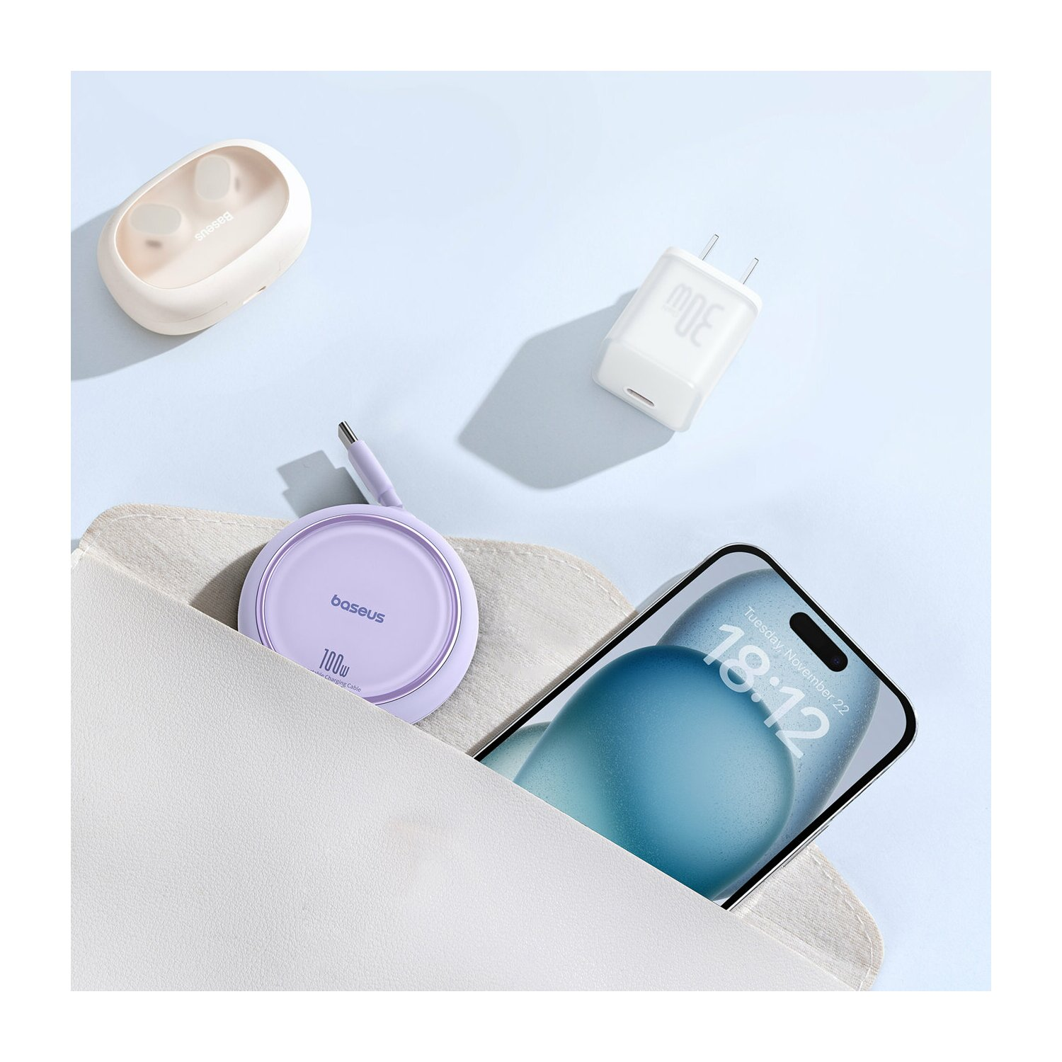 Telefon, ładowarka i słuchawki w białej torbie na niebieskiej powierzchni. Telefon pokazuje datę i godzinę.