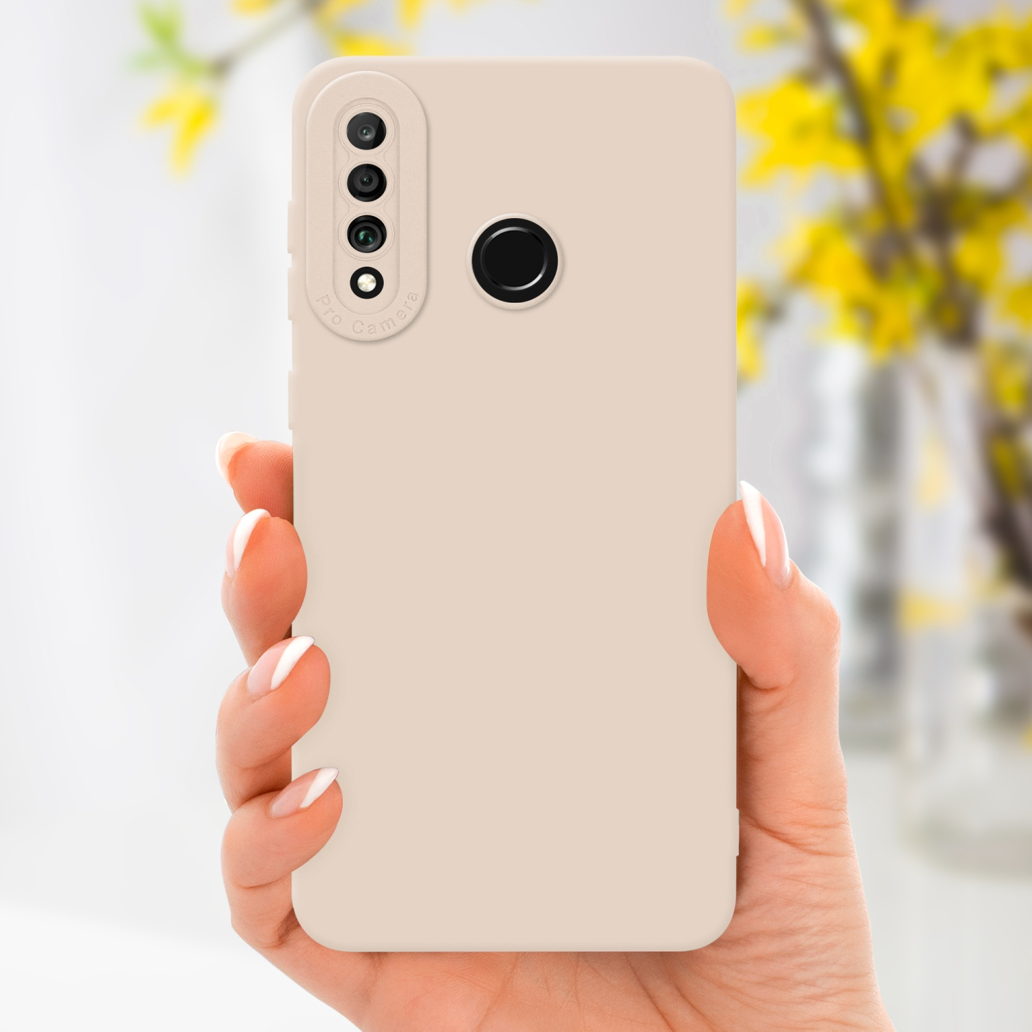 Una mano tiene una custodia beige con un rigonfiamento della fotocamera. Fiori gialli sfocati sullo sfondo.