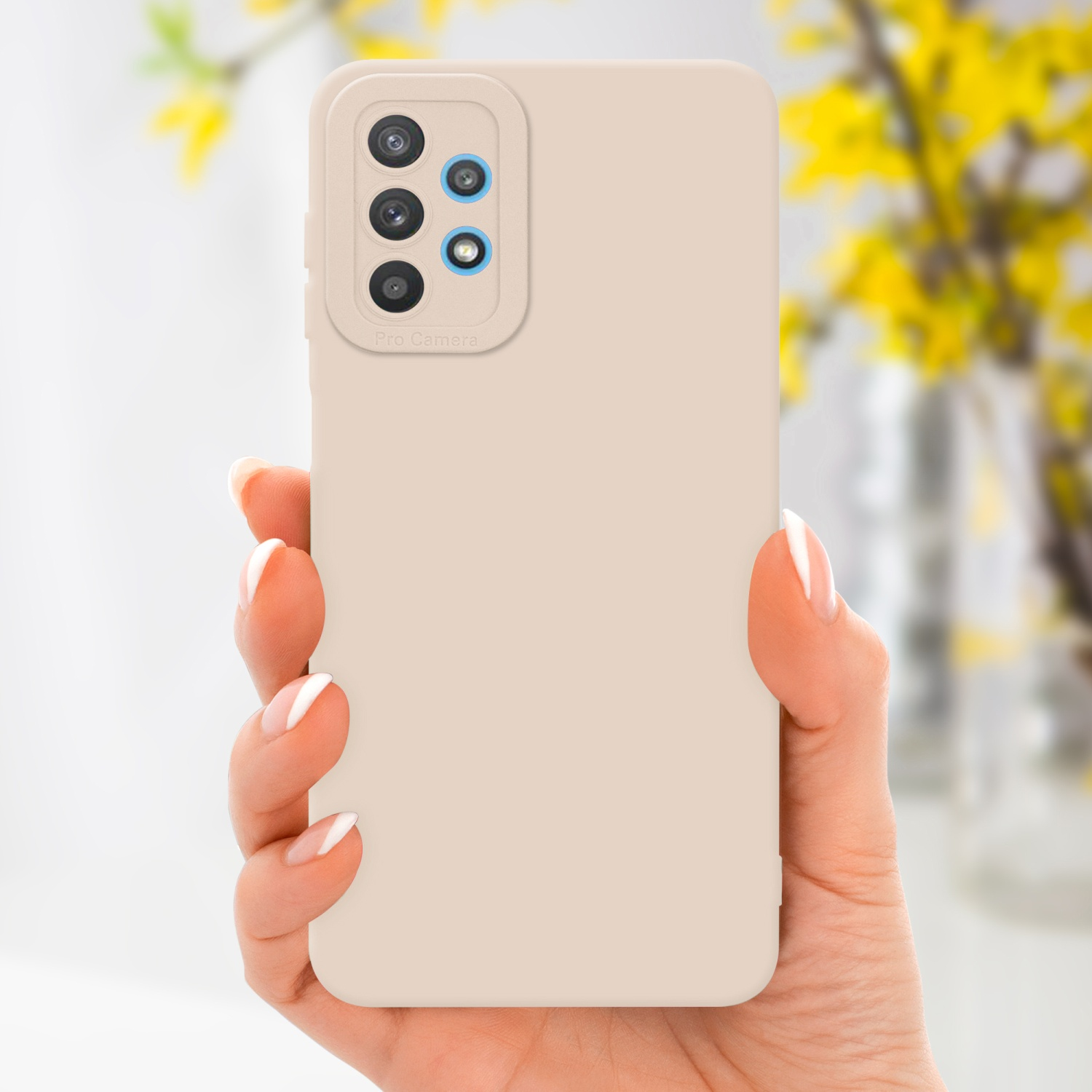 Main tenant un étui de téléphone beige avec bosse de caméra. Fleurs jaunes floues en arrière-plan.