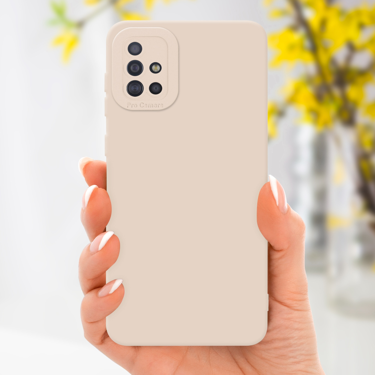 Main tenant une coque beige avec caméra, sur fond flou avec fleurs jaunes.