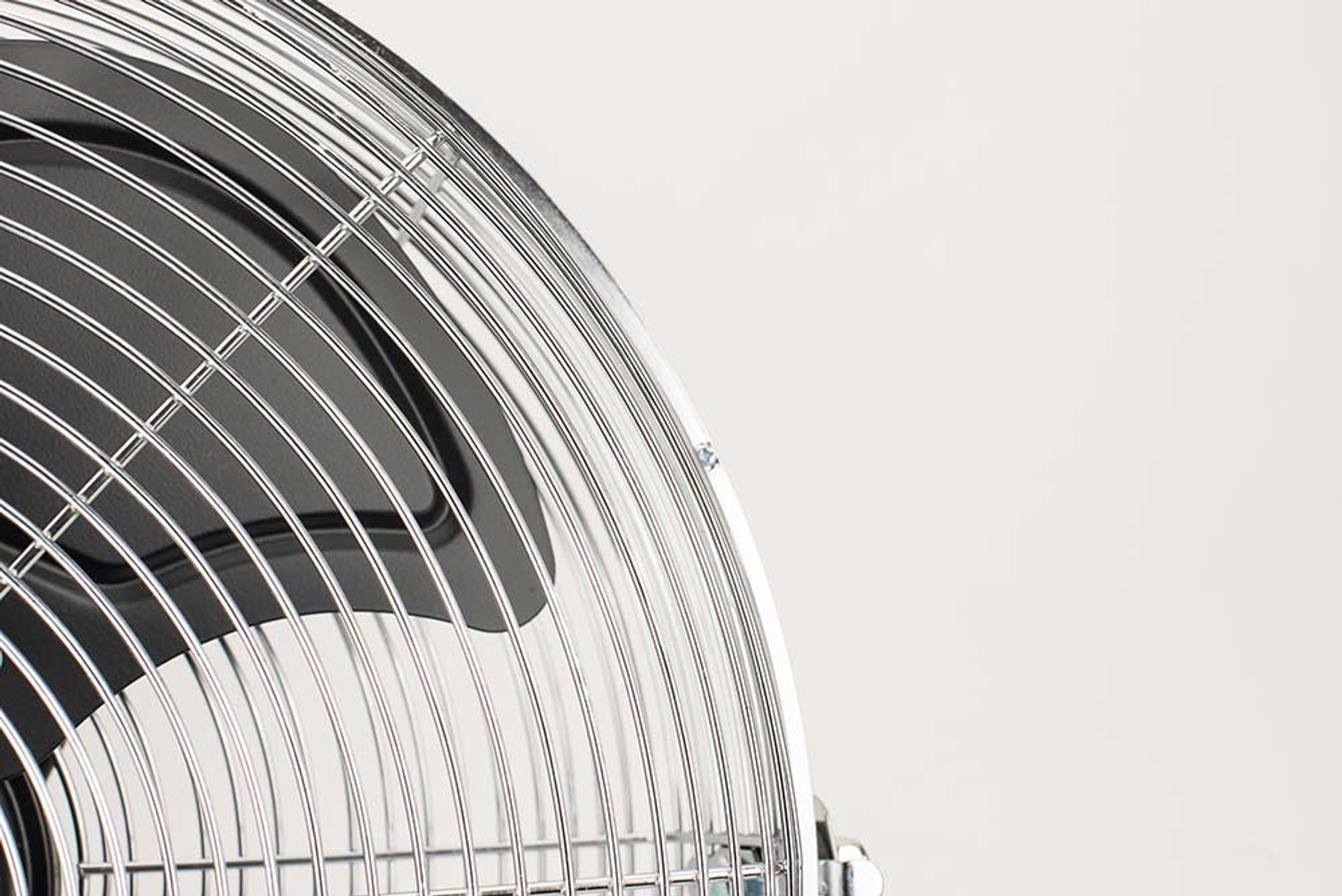 Una gabbia di ventola in metallo con una ventola nera e uno sfondo bianco. La gabbia è curva.