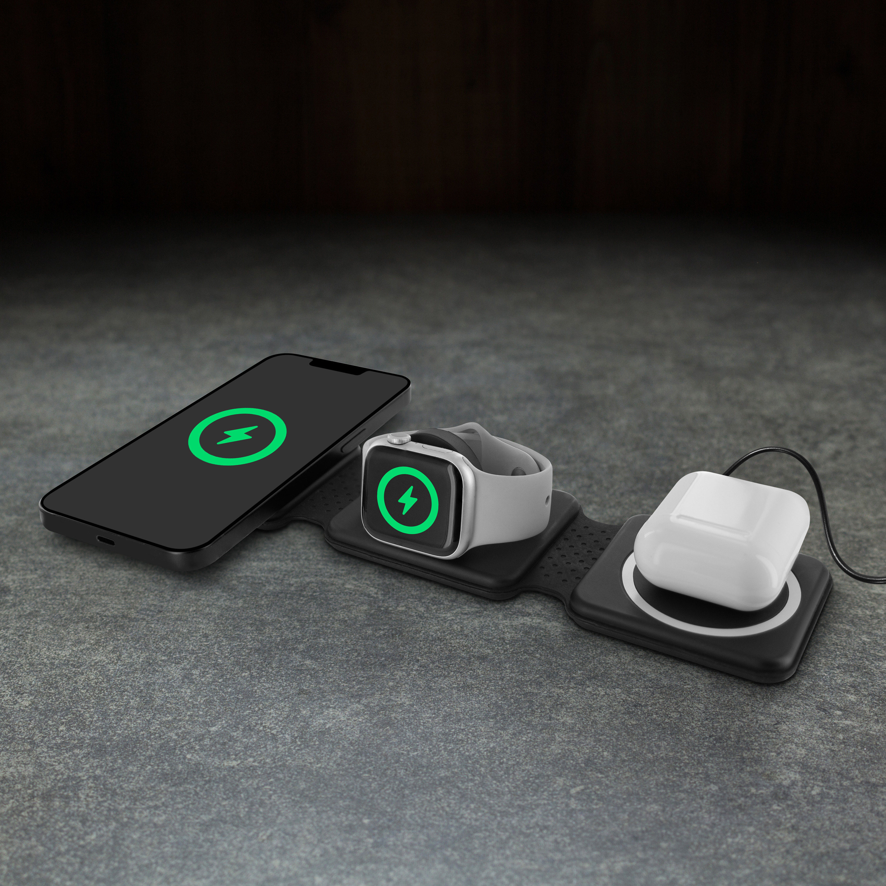 Una estación de carga para teléfono, reloj y auriculares en una superficie de piedra. Cada artículo tiene un símbolo de carga.