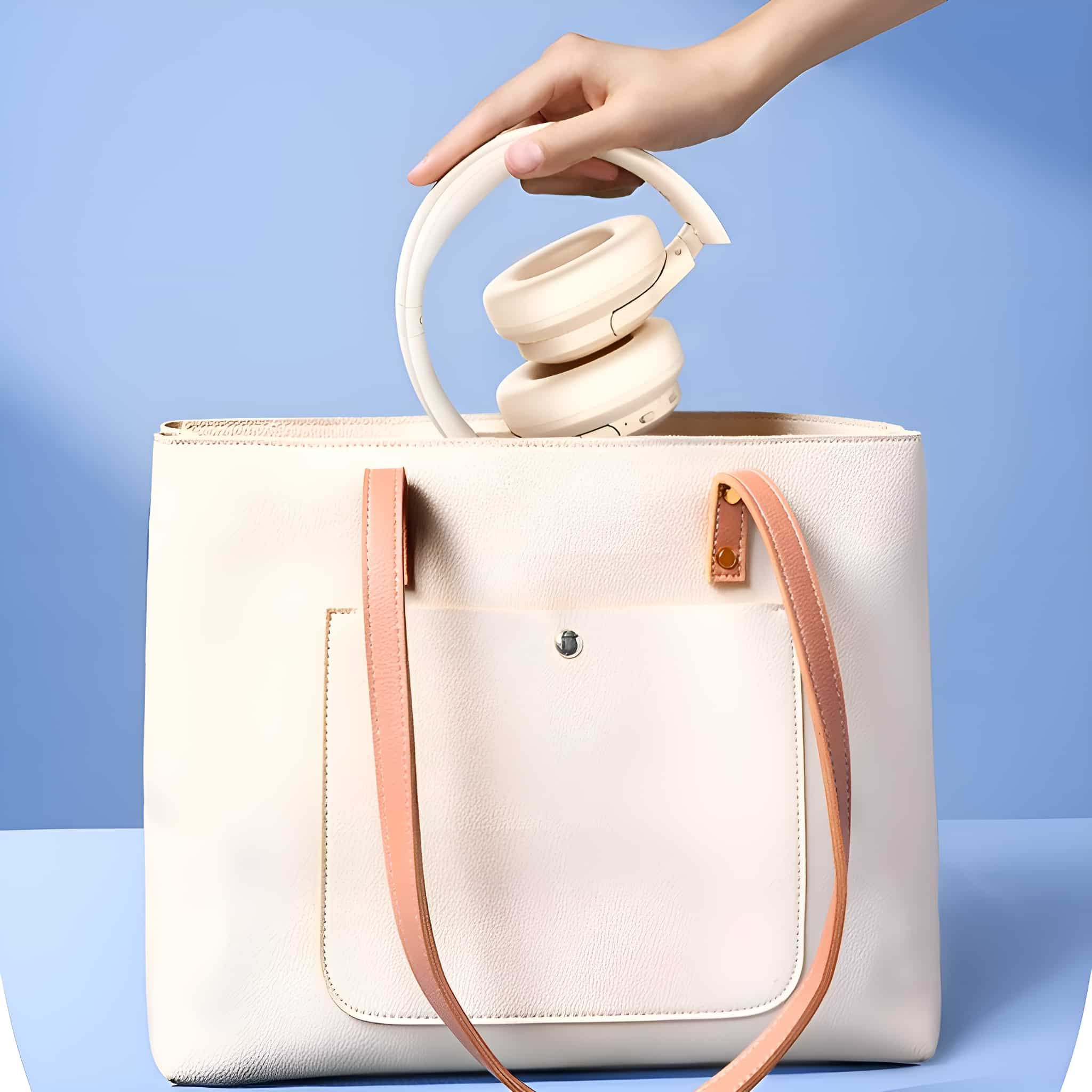 Cremefarbene Kopfhörer werden in eine passende Handtasche gelegt.