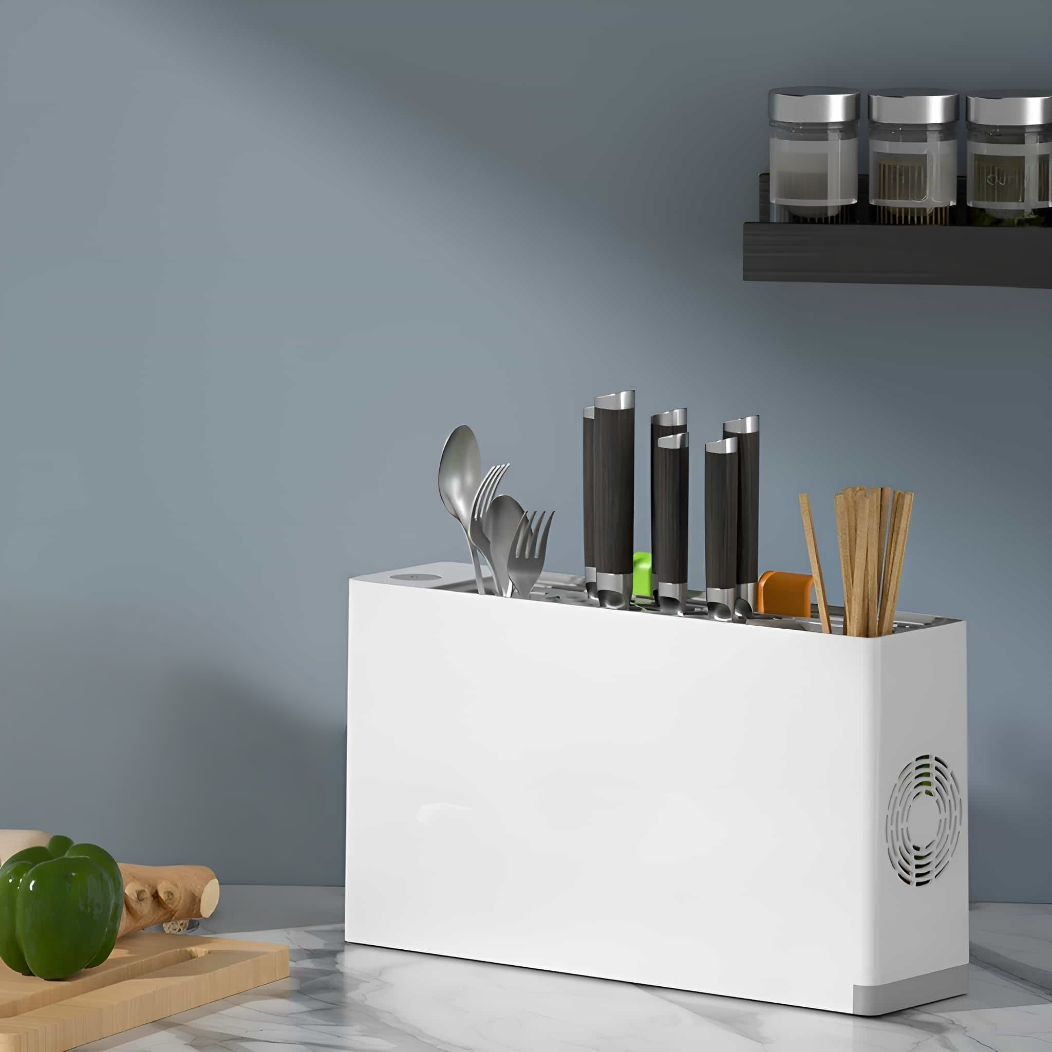 Weißer Küchenutensilienhalter mit Utensilien und Gewürzen im Hintergrund auf einer Theke.