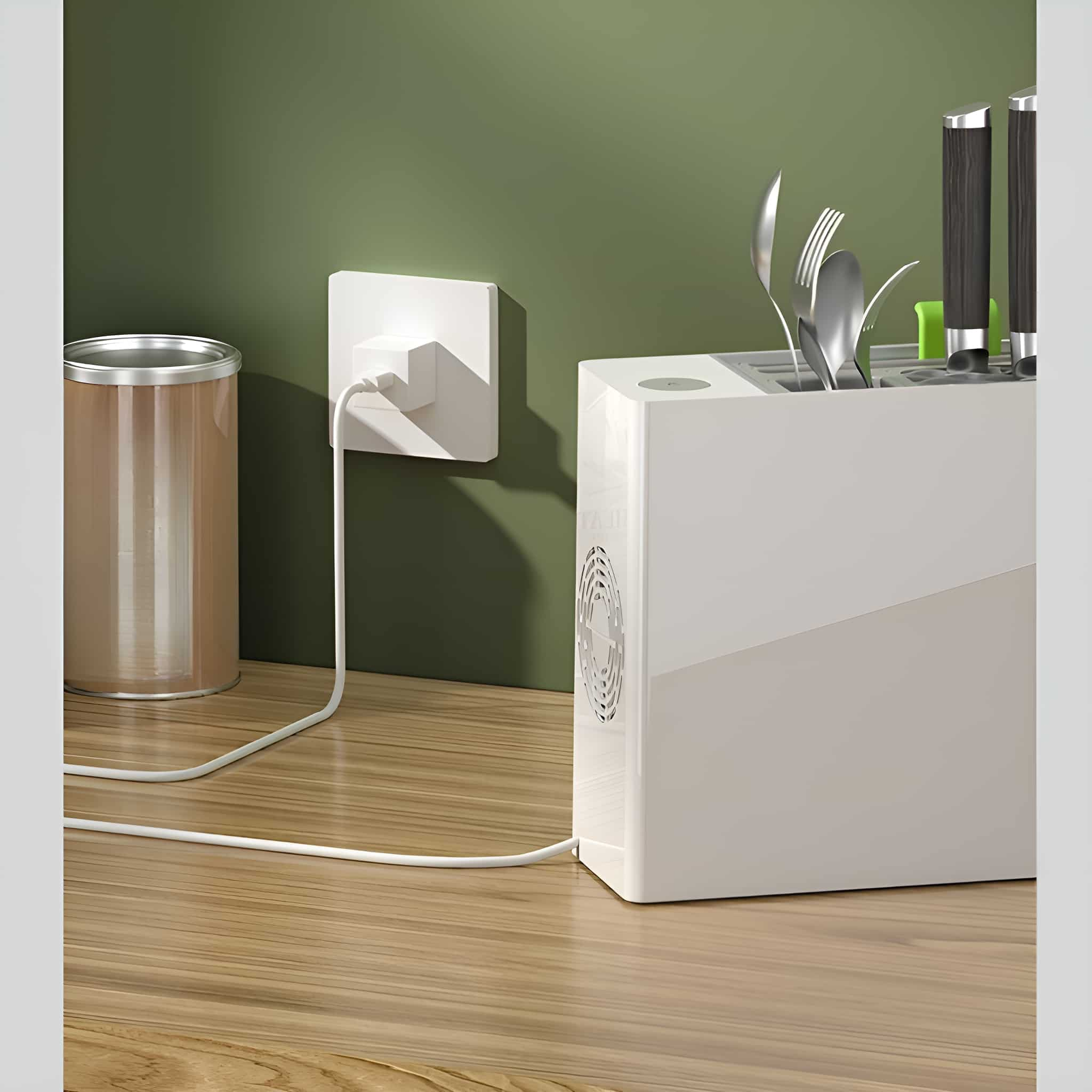 Eine weiße Ladestation mit Stecker in einer Steckdose. Eine grüne Wand und ein Holztisch.