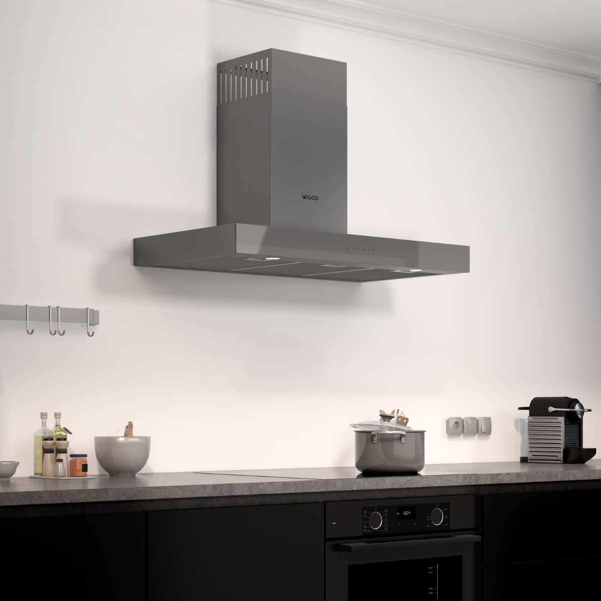 Cuisine avec une hotte grise au-dessus d'une table de cuisson et d'un four noirs. Casseroles en acier inoxydable.