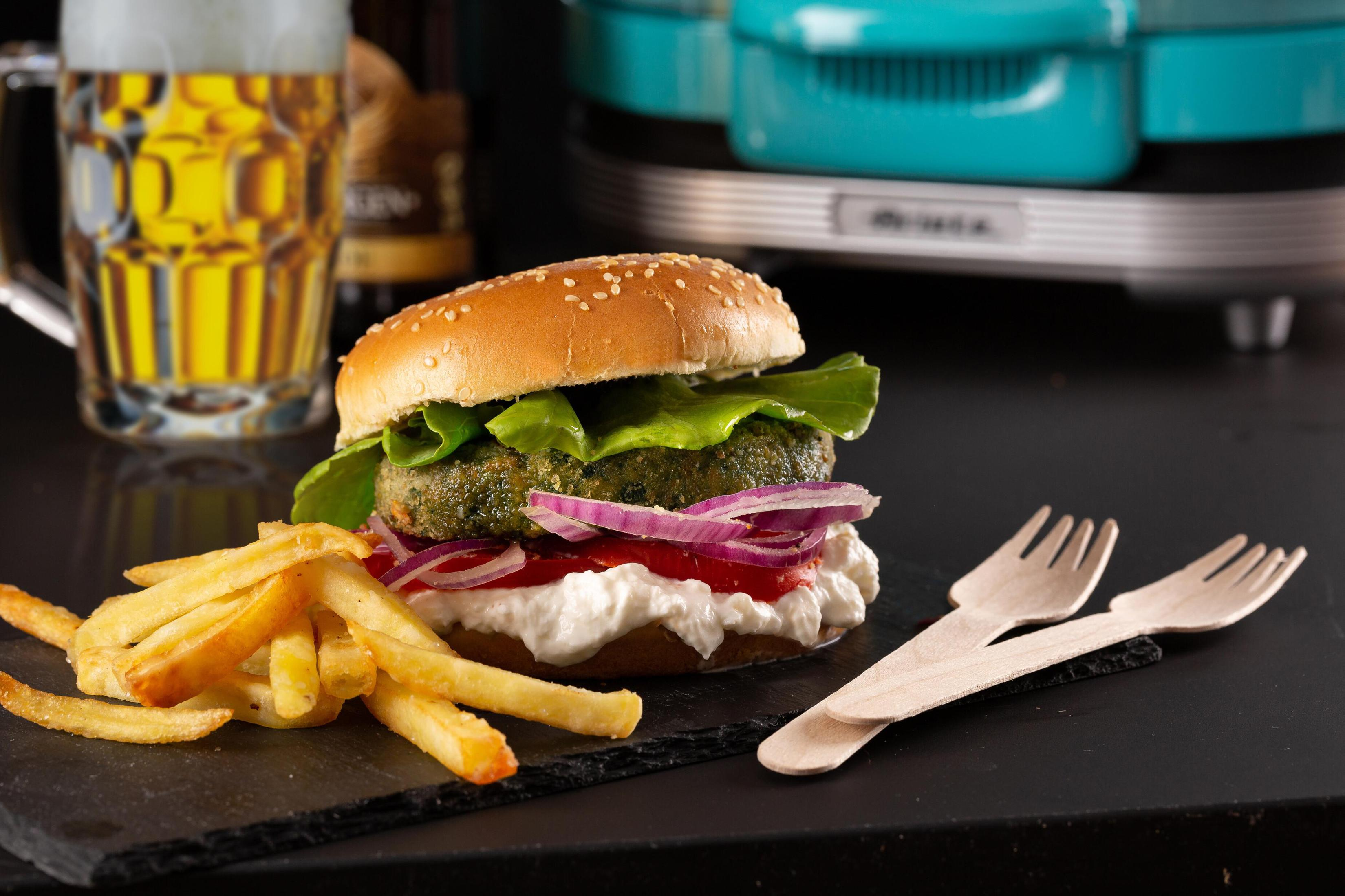 Burger met friet en een biertje. Donker oppervlak, wazige achtergrond.