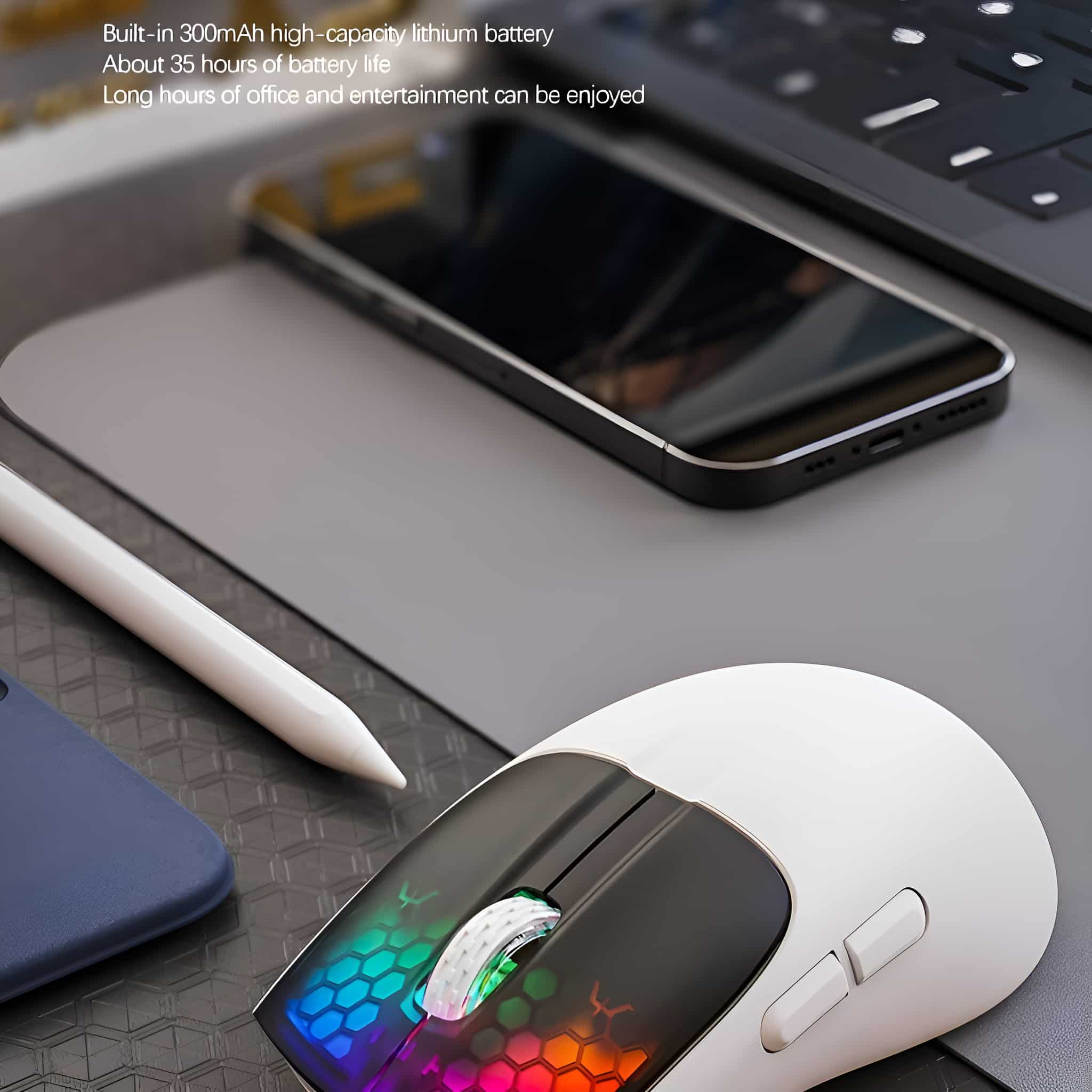 Eine weiße Maus mit schwarzem Oberteil und farbiger Beleuchtung. Ein Telefon und Laptop im Hintergrund.