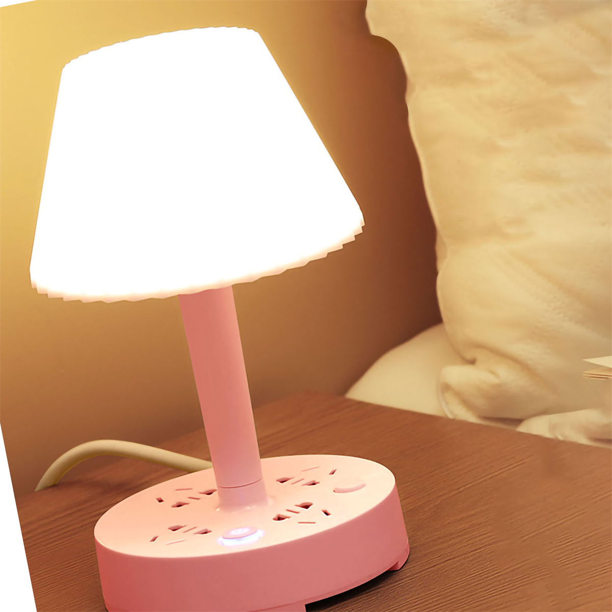 Pinke Nachttischlampe mit Steckdosenleisten-Sockel und beleuchtetem Schirm.
