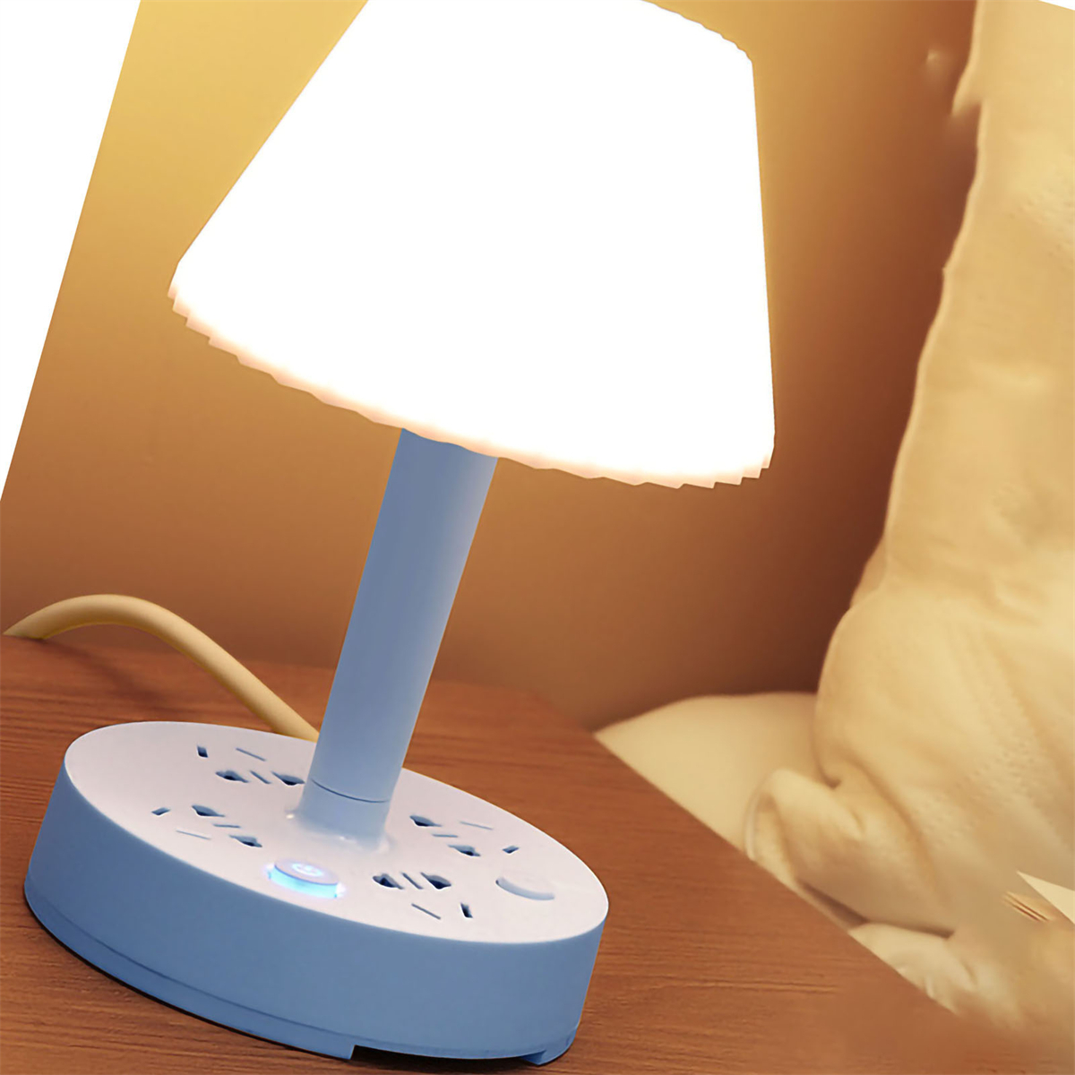 Eine blaue Nachttischlampe mit mehreren Steckdosen auf der Basis steht auf Holz.