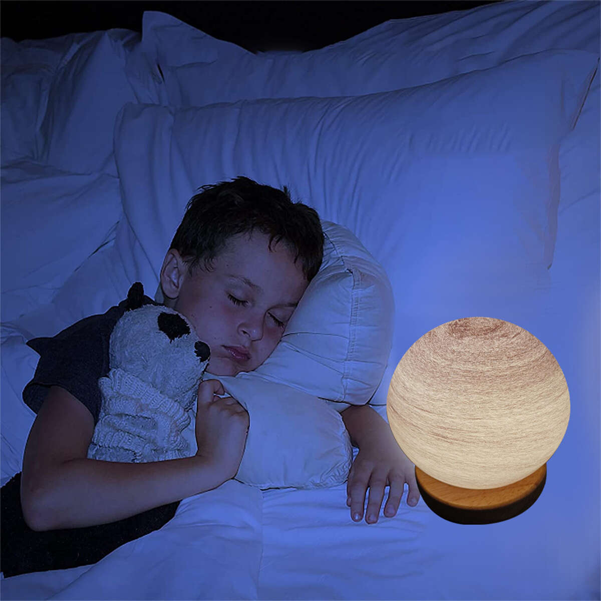Junge schläft im Bett mit einer runden Lampe. Weiße Kissen und ein Stofftier sind zu sehen.