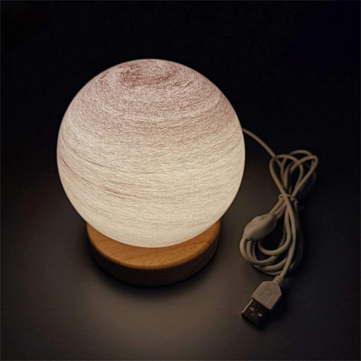 Eine kugelförmige Lampe mit Holzsockel und USB-Kabel auf dunkler Oberfläche.