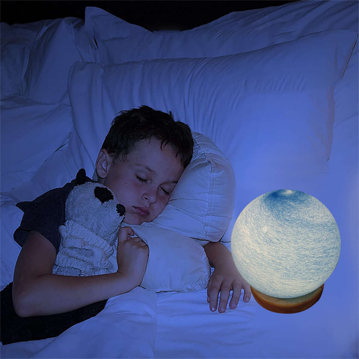 Junge schläft im Bett mit Stofftier. Mondförmige Lampe auf dem Nachttisch.