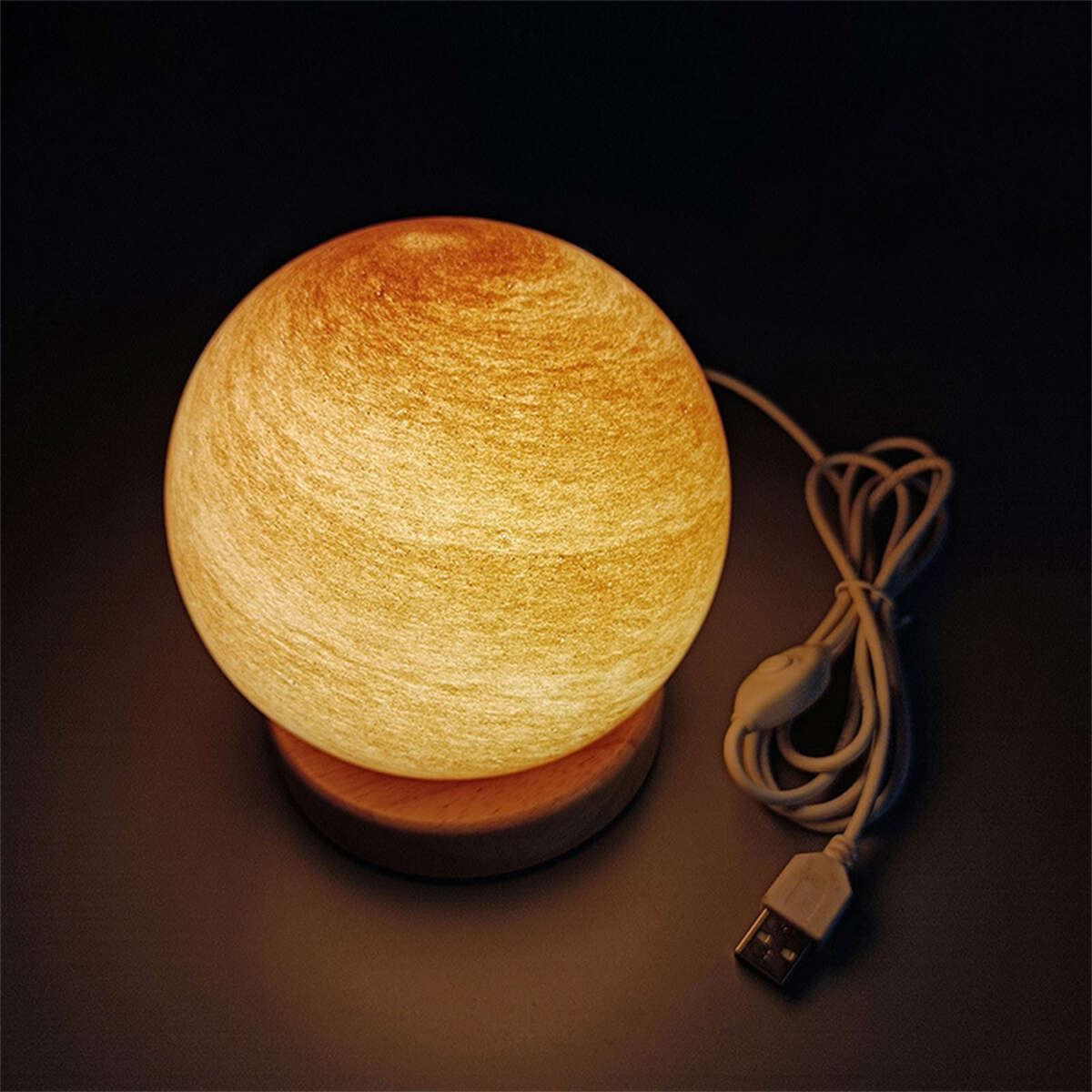 Gelb-orangefarbene Kugellampe auf Holzsockel, mit Kabel und USB-Anschluss.