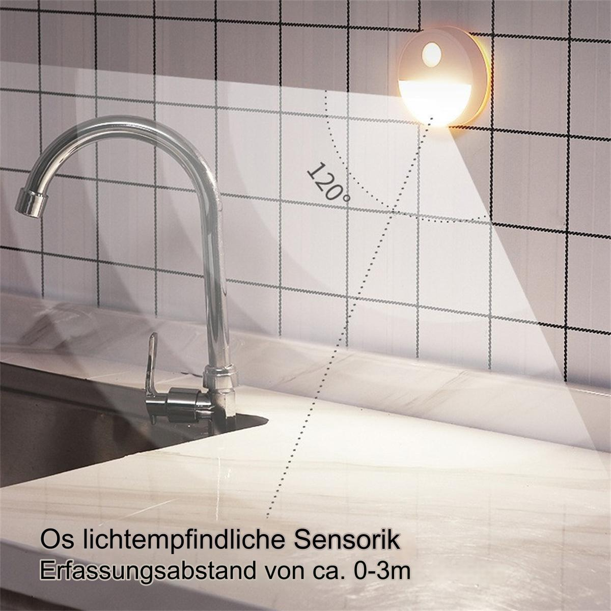 Eine weiße Wand mit silbernem Wasserhahn, Licht mit beleuchteter Fläche und Text auf Deutsch.