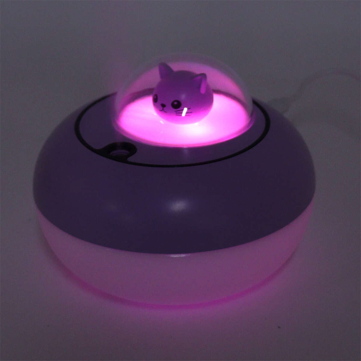 Lila-weißer Luftbefeuchter mit katzenförmigem Aufsatz. Rosa Licht beleuchtet die Katze.