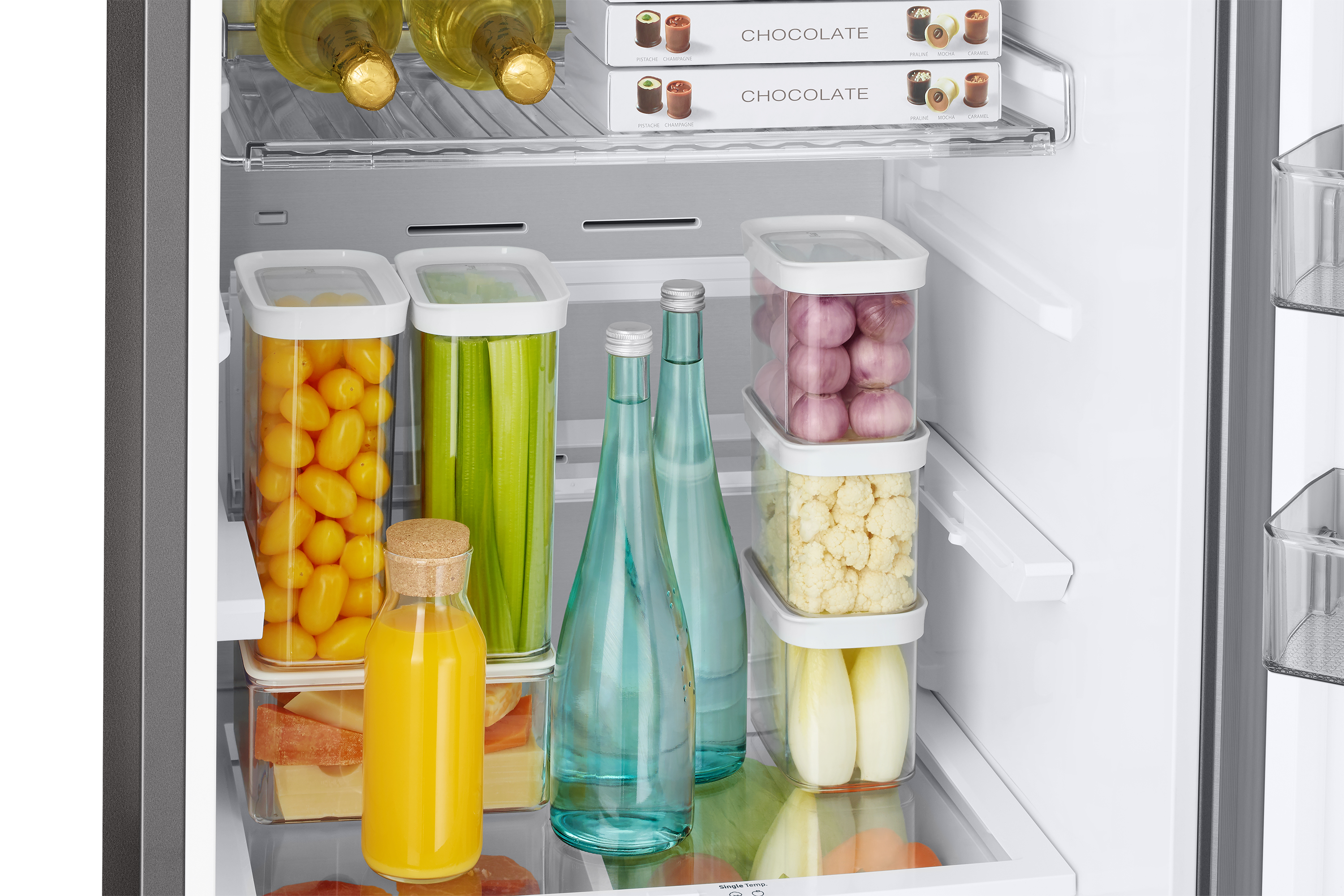 Wnętrze lodówki wypełnione produktami spożywczymi w pojemnikach i butelkach.